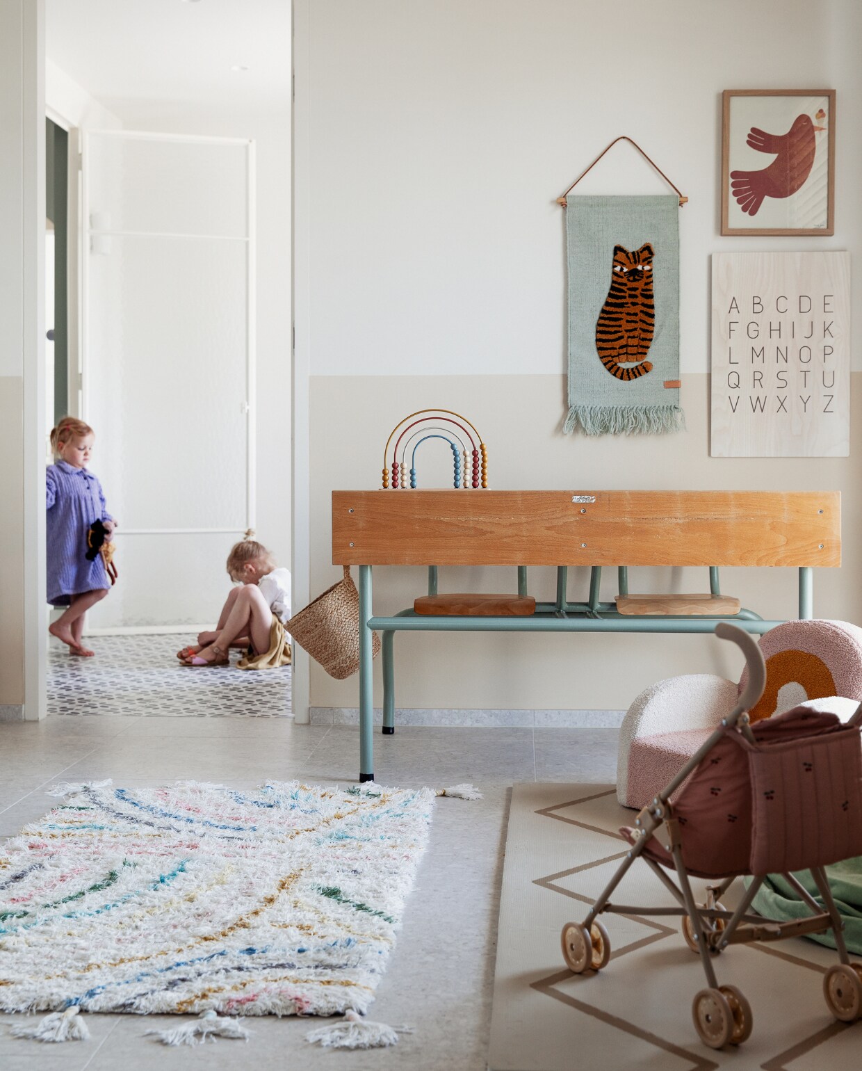 Schoolbank kringloop, vloerkleed KidsDepot, regenboogstoel Maisons du Monde, wandkleed Oyoy, letterposter Kwantum, muurkleur lambrisering Joa’s White van Farrow &amp; Ball, gietvloer kleurcode NCS S2000N van Alterieur. Overig onbekend. vtwonen 11-2023 | styling Ilona Jongepier | fotografie Dana van Leeuwen