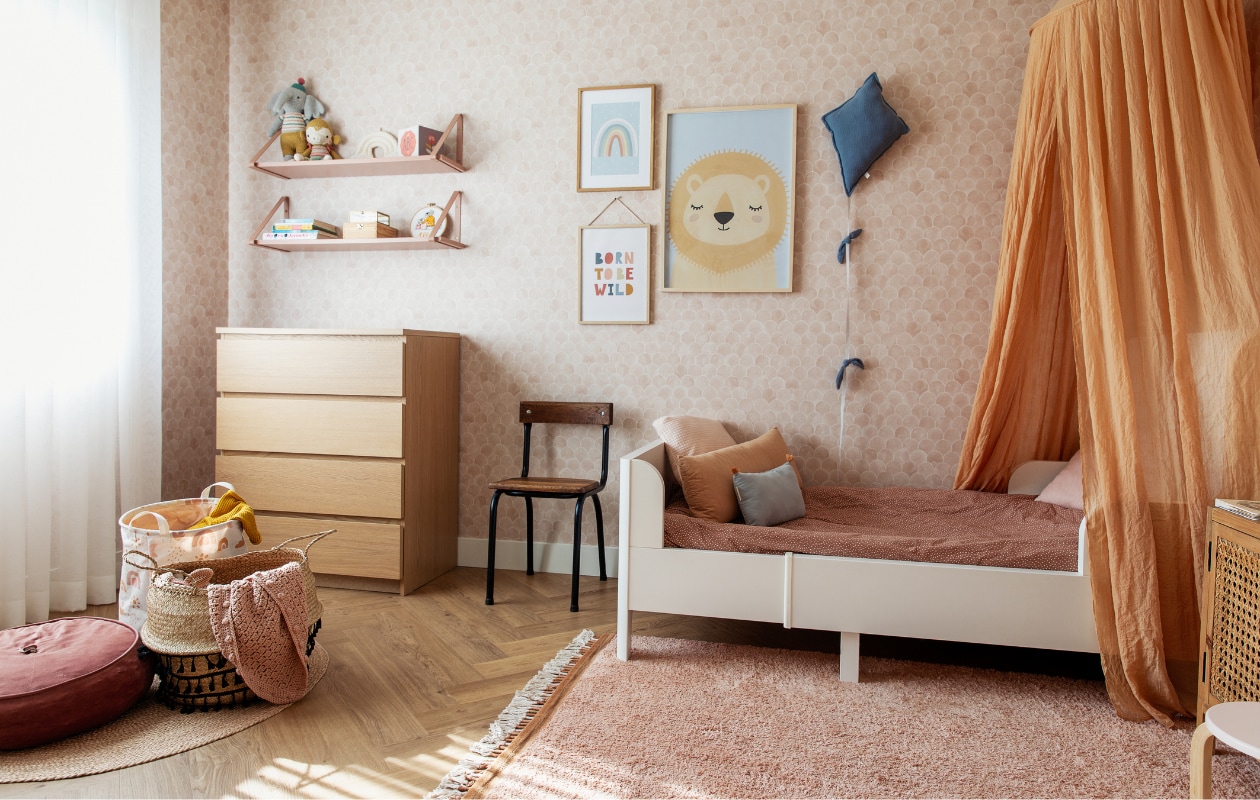 Wandplanken Ferm Living. Knuffels, borduurring met geboortekaartje en vlieger zelfgemaakt. Ladekast Ikea, posters Postery, hemel Jollein, bedlinnen Zara Home, stoel tweedehands, nachtkastje Kwantum, vloer Anago van Floorify. Overig onbekend. vtwonen 11-2023 | styling Ilona Jongepier | fotografie Dana van Leeuwen