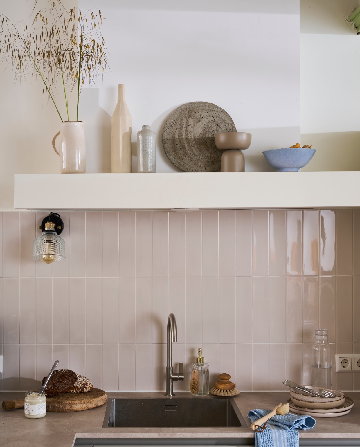 Composiet spoelbak met goudkleurige kraan, prijs op aanvraag.  Wandtegels Shapes in Vapor van vtwonen per m2 € 59,-. M.m.v. hm.com (kom, borden, theedoek, schaal op voet, kan, serviesgoed, bord), bolia.com (karaf, vaas) vtwonen catalogus 2023