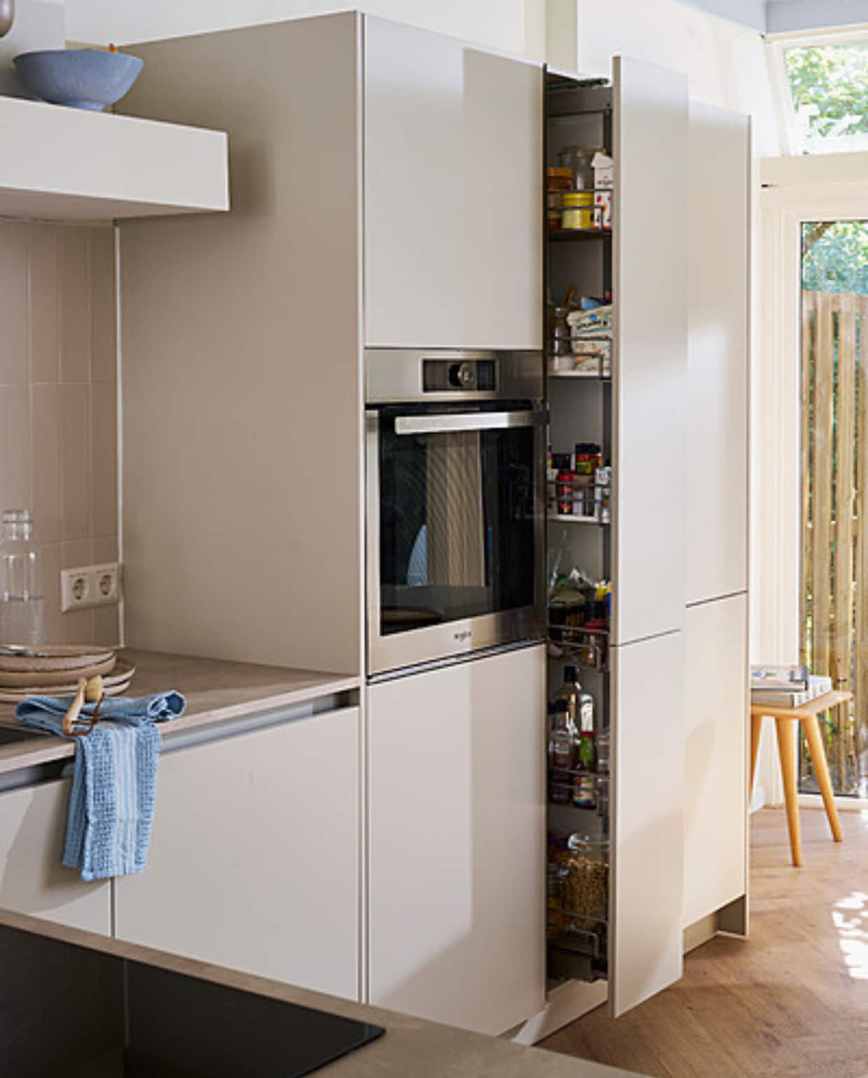Keuken Basic Greige met diverse formaten opbergkasten, prijs op aanvraag. M.m.v. hm.com (kom, borden, theedoek, demachinekamer.nl (houten kruk). Overig privébezit. vtwonen catalogus 2023