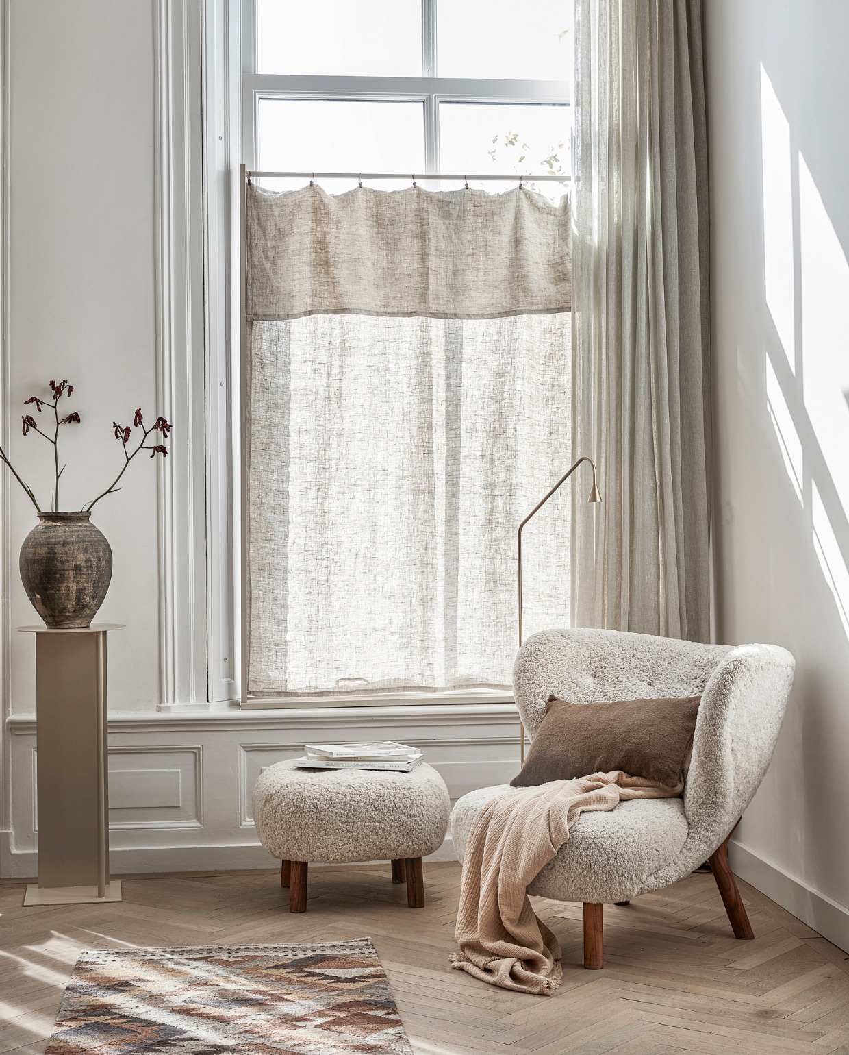 Plaid, 140x190 cm € 59,99, vloerkleed, 70x200 cm € 179,-, bruin wollen kussen, 30x50 cm € 39,99 (zarahome.com). Vloerlamp Brass Austère € 899,- (thefinestore.com). Fauteuil Little Petra met schapenvacht en notenhouten poten € 4691,-, poef Little Petra € 1442,- (andtradition.com). Pedestal in kleur Cashmere van Ferm Living € 191,99 (vtwonen.nl). Antieke pot € 79,- (weldaad.com). Linnen stof, per strekkende meter € 24,95 (stof.nl). Koperkleurig gordijnringen met klem, set van 6 € 1,80 (jandegrotekleinvakman.nl). Verf raamframe kleur Joanna (littlegreene.nl). Overgordijnen, tijdschriften privébezit. vtwonen 13-2022 | styling Kim van Rossenberg | uitvoering Richard van Meerveld | fotografie Peggy Janssen