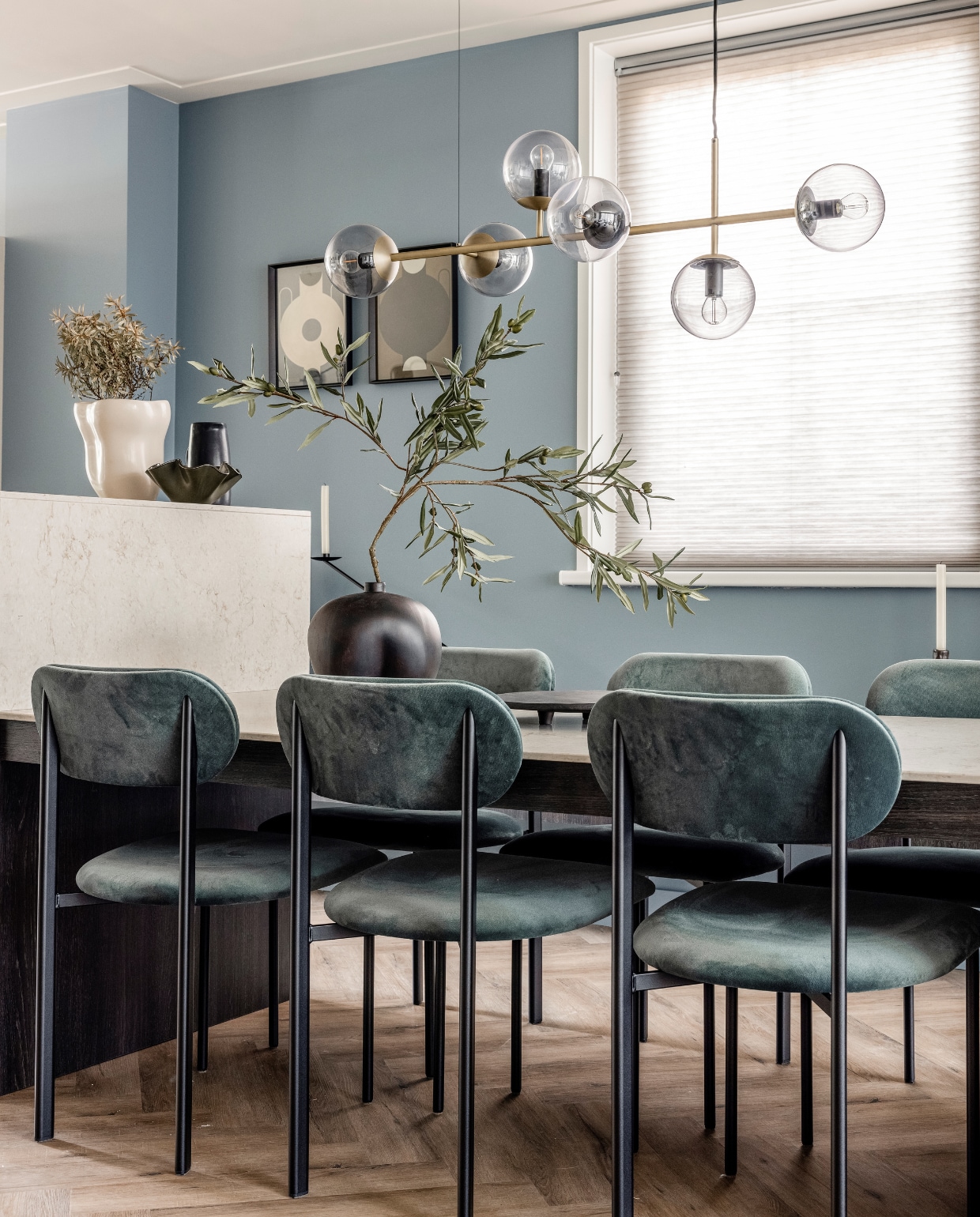 Eettafel vanaf € 3850, (meijermaatinterieurs.nl). Composiet tafelblad in verstek Caesarstone in 5212 Taj Royal, prijs op aanvraag (ligtvoetnatuursteen.nl). Hanglamp van Bolia € 765,-, kandelaar van Ferm Living € 39,- (vtwonen.nl). Eetkamerstoelen, per stuk € 449,-, zwarte vaas op tafel € 119,-, zwart dienblad op tafel € 129,- zwarte schaal op tafel € 70,-, ronde zwarte vazen op het dressoir, klein € 39,- en groot € 49,-, schaal op het dressoir € 49,- (eijerkamp.nl). Handgemaakte keramische lampenvoet met kap € 300,- (angeliquehomberg.nl). Linker poster Circular Vase € 49,-, rechter poster Silhouette Of A Vase € 49,- (theposterclub.com). Zwarte kan € 24,99, zwarte golvende schaal € 12,99, beige vaas € 39,99 (hm.com). Zwarte fotolijsten, per stuk € 12,50, kaarsen, per stuk € 1,- (hema.nl). Olijftakken, prijs op aanvraag (silk-ka.com). Overig privébezit. Weer verliefd op je huis seizoen 17 aflevering 4 | styling Liza Wassenaar | fotografie Sonja Velda