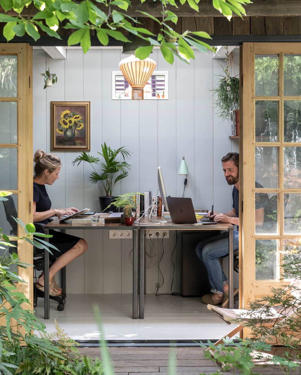 Tuinhuis ontworpen door Philip en gemaakt door timmermannen Jan en Rob. Deuren ’t Achterhuis. Planken op muur van oude schuren via Historisch Hout, net als de scheepsplanken op de veranda. Glas-in-loodraampje Marktplaats. Hanglamp Taiwan-lantern. Bureaus gemaakt door Mariekes vader. Schilderij aan muur uit Philips familie. Plantenhangers Mica. Wandlamp rommelmarkt IJ-Hallen. Strandstoel al jaren in bezit, herkomst onbekend. vtwonen 04-2020 | fotografie Margriet Hoekstra