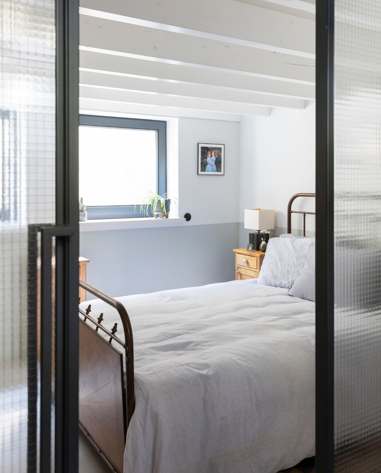 Glazen wanden scheiden de logeerkamer van het washok. Bed Marktplaats. Sprei House in Style. Nachtkastje van Mariekes oma. Lamp Kwantum. Foto aan muur door Marieke geruild met collega Vivian Keulards, ingelijst bij Jollijst. vtwonen 04-2020 | fotografie Margriet Hoekstra