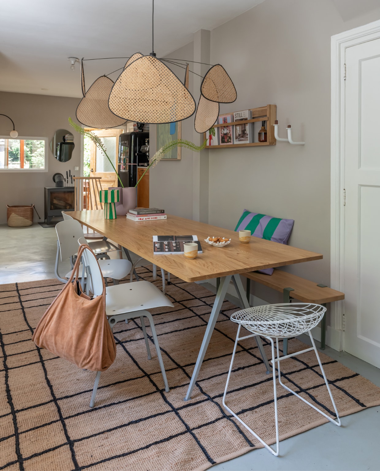 Cementdekvloer met coating RAL7038, muurverf Elephant’s Breath van Farrow &amp; Ball, vloerkleed Jotex. Eettafel, witte stoelen Revolt en houten spijlenstoel van Hay. Kruk Pastoe, houten bank Tiptoe, kussen Fést, vaas Kink van Muuto, wandplank zelfgemaakt, hanglamp Market Set, wandkandelaars Studio Frederik Roijé. Overig onbekend. vtwonen 12-2023 | styling Sharon Roest | fotografie Caroline Martinot
