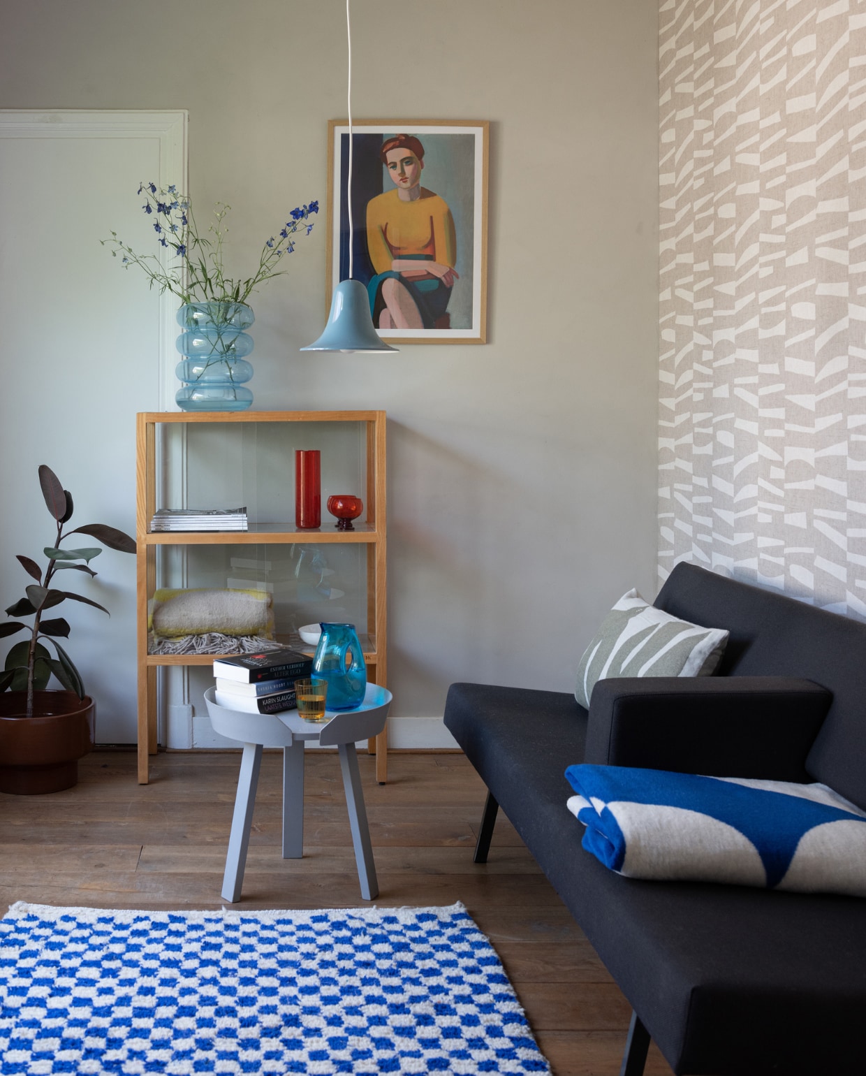 Muurverf Dora van Betonlook, behang Twist van Eijffinger, vloer onbekend. Tweedehands slaapbank Martin Visser voor Spectrum, kussen Brita Sweden, plaid Noo.ma, vloerkleed uit Marrakech, bijzettafel Muuto, hanglamp Verner Panton, vitrinekast HKliving, blauwe vaas Fést, glaswerk Polspotten, ingelijste poster Vilhelm Lundstrøm van Pstr Studio. vtwonen 12-2023 | styling Sharon Roest | fotografie Caroline Martinot