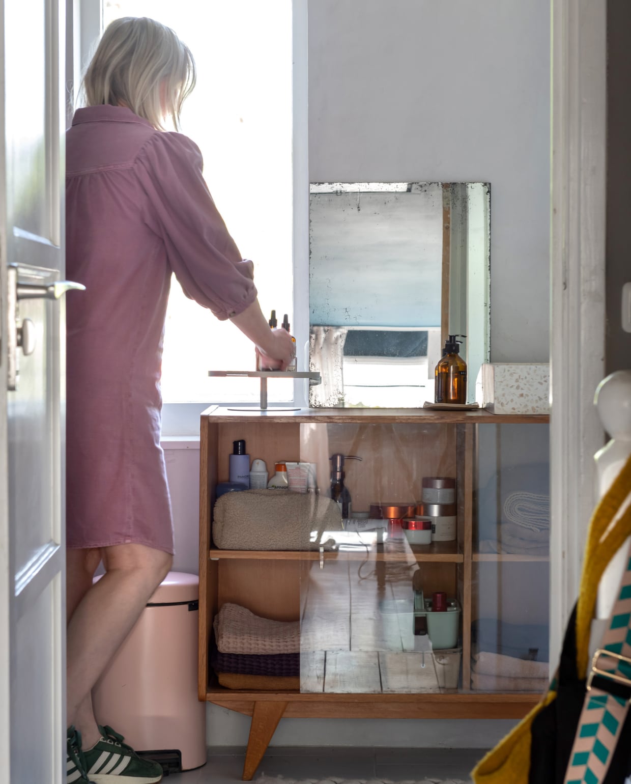 Een vintage vitrinekast van Pakhuis Noord fungeert als handdoekenkast in de badkamer. Prullenbak Brabantia. Overig onbekend. vtwonen 12-2023 | styling Sharon Roest | fotografie Caroline Martinot
