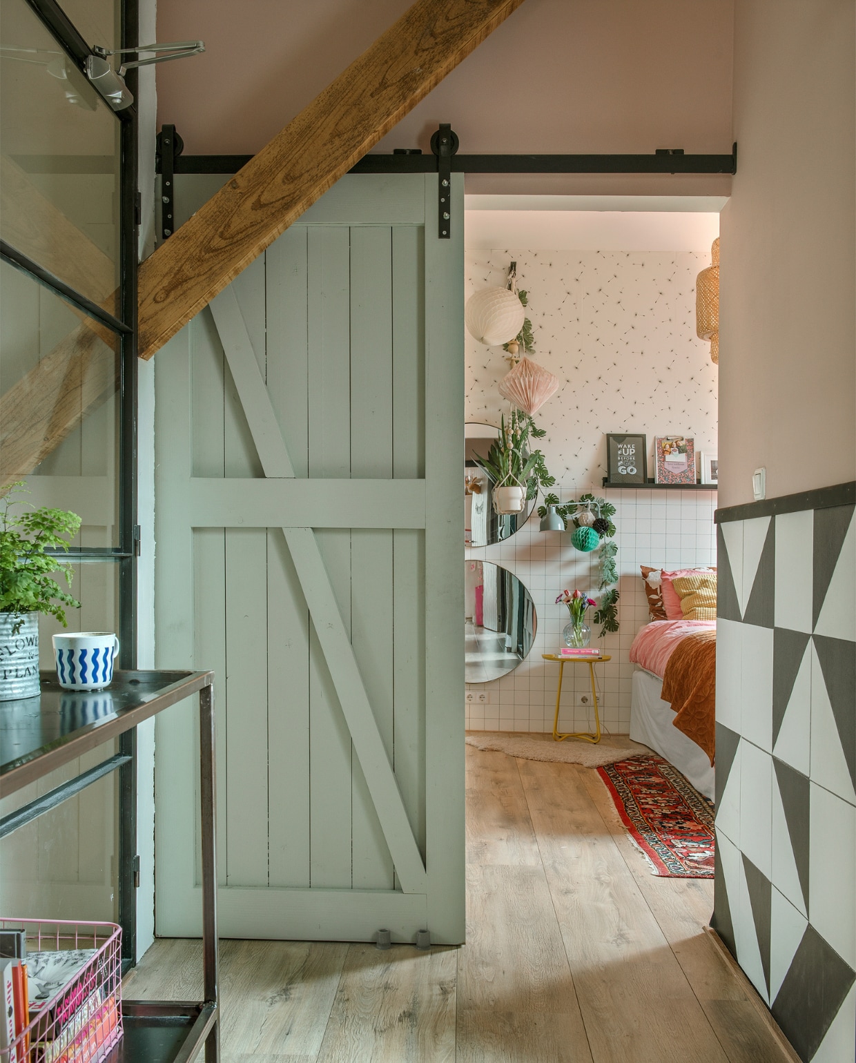 Schuifdeur gemaakt door Bouwbedrijf J. Van Engelen, rails en open kast naar eigen ontwerp gemaakt door de lokale smid. Behang Karwei. Boxspring en beddengoed Ikea. Spiegels en geel tafeltje Kwantum. Perzisch vloerkleed Marktplaats. Overig onbekend. vtwonen special DIY 6-2022 | fotografie Ton Bouwer