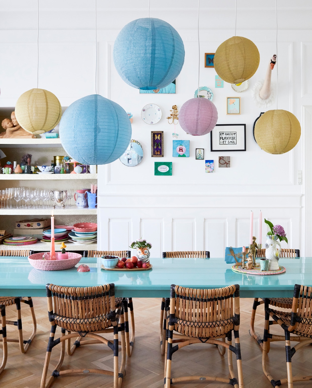 Charlotte bestelde de eettafel bij een lokale timmerman en verfde hem turkoois. Mooi met de naturelkleuren van de rotan stoelen van Cane-Line. Servies, vazen, lampions en kaarsenhouders van Rice. vtwonen 06-2019 | fotografie Stine Christiansen