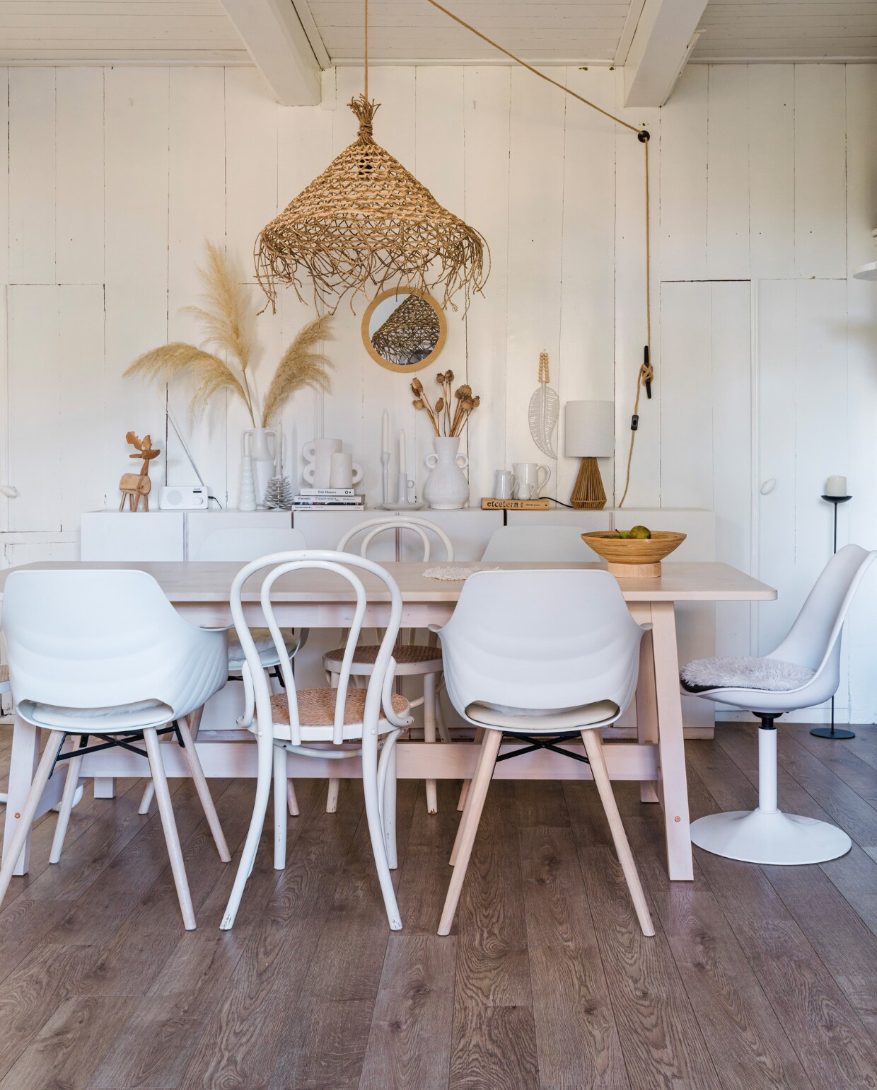 Tafel Marktplaats, kuipstoelen Vestbjerg. Thonet-stoelen en draaistoel Marktplaats. Hanglamp Led There Be Light, jute snoer Karwei, vloerkandelaar K’willeminhuis, vloer Quick-Step. Verf wand en plafond Ral 9016. Dressoir van drie Ivar-kasten van Ikea, wit geschilderd. Op het dressoir: twee vazen links Karwei, vaas rechts Gusta, kandelaars Ikea, kaarsenhouder dennenappel MK Objecten, tafellamp Wehkamp, melkkan Dille &amp; Kamille. Spiegel Kwantum, porseleinen veer Madumadu. Overig onbekend. vtwonen 12-2023 | styling Anouschka Witteveen | fotografie Corine Hoge Bavel