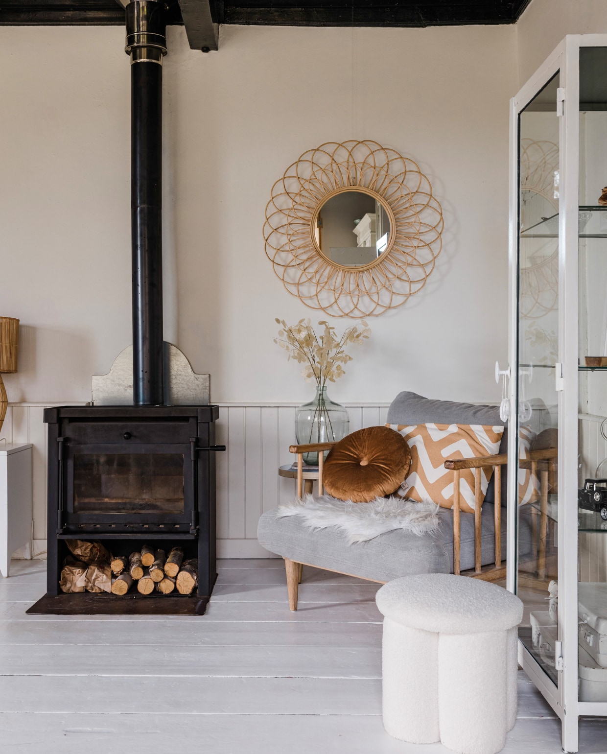 Kachel zat al in het huis. Fauteuil Loods 5, bruin kussen Dutch Decor, bruin-wit kussen H&amp;M Home. Vacht en bijzettafel Kwantum. Poef Karwei, vitrinekast van vtwonen, wit geschilderd. Spiegel Leen Bakker, gistfles brocantemarkt, kunstbloemen Jysk. Overig onbekend. vtwonen 12-2023 | styling Anouschka Witteveen | fotografie Corine Hoge Bavel