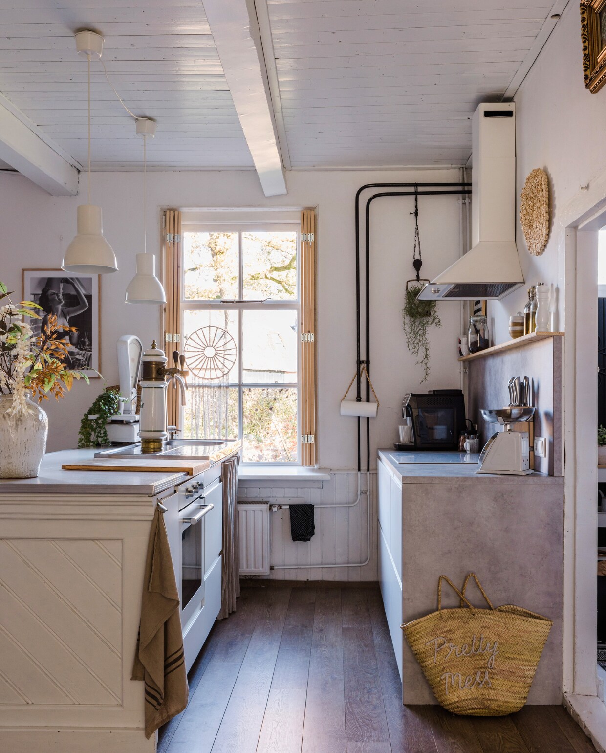 Macramé hanger, luiken, gordijn onder spoelbak en keukenrolhouder zelfgemaakt. Keukenkasten, betonlook werkblad, apparatuur, barkrukken, lampen, messenblok, glazen flessen, pepermolen en snijplank Ikea. Bar en antieke Grolschtap stonden al in het huis, geschilderd in Ral 9016. Koffiemachine Philips. Theedoek Loods 5, tas Noa May, Berkel-weegschaal Marktplaats, zwart-wit poster Poster Store. Vaas en zijden bloemen MK Objecten. Kommen HKliving, koffiekoppen Douwe Egberts, zwarte handdoek Hema, vloer Quick-Step. Verf muren en lambrisering Ral 9016. vtwonen 12-2023 | styling Anouschka Witteveen | fotografie Corine Hoge Bavel