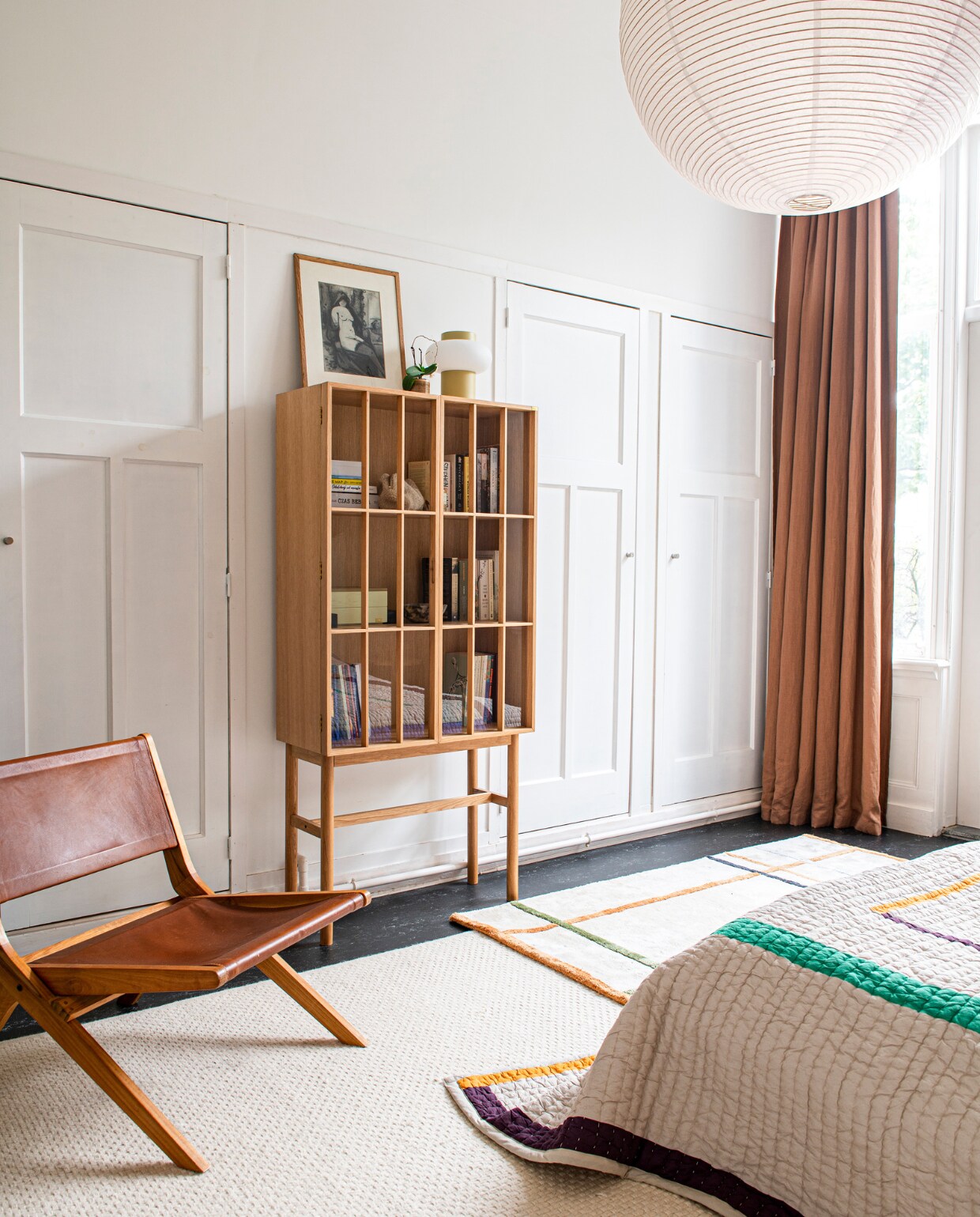 Kast, gestreept vloerkleed en sprei Hübsch. Hanglamp Ikea, muurverf Kalkliter, gordijnen hingen er al. Overig onbekend. vtwonen 12-2023 | productie De Binnenkijkers | styling  Jeske Weel | fotografie Caroline Coehorst