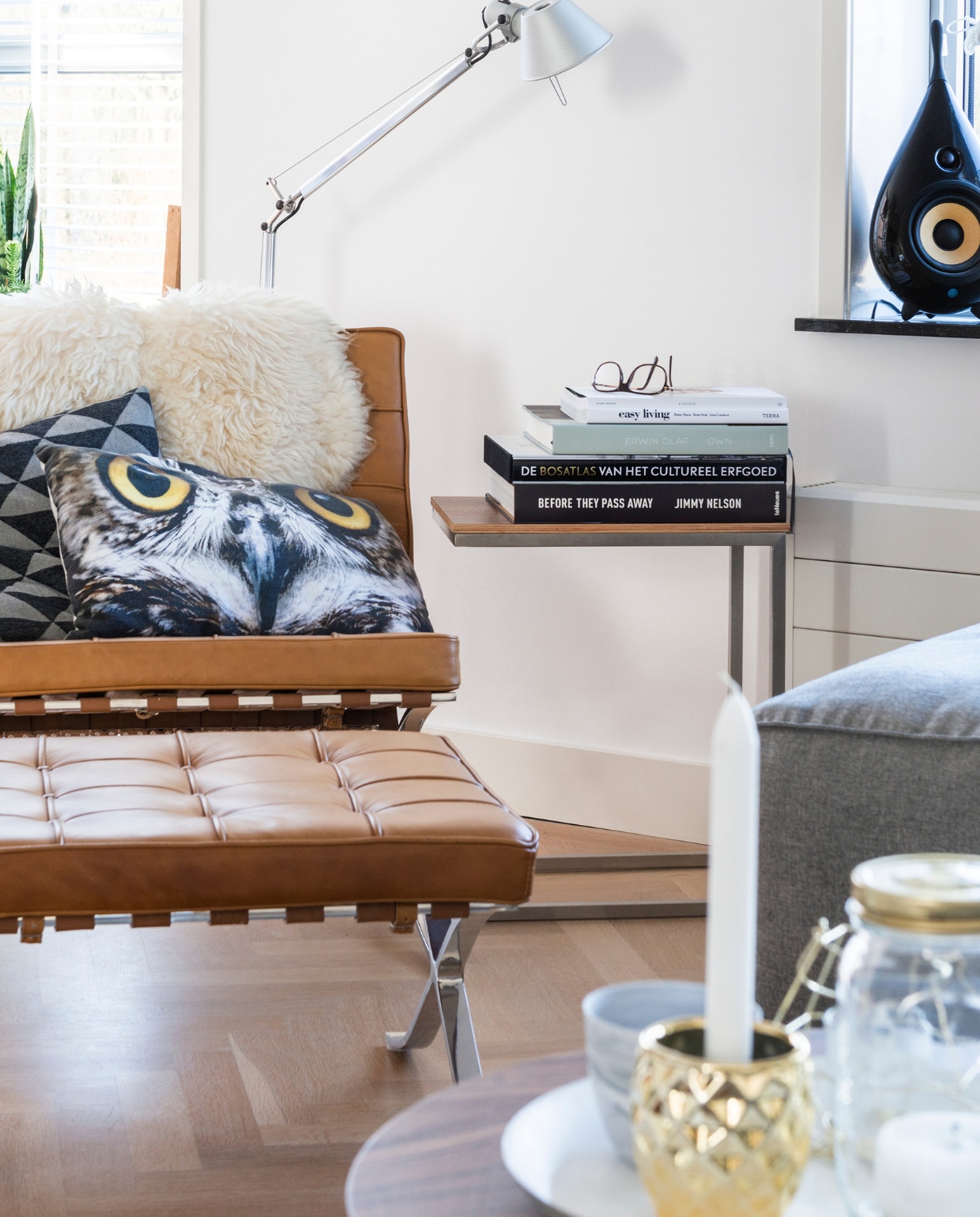 Glazen pot van Dille en Kamille, dienblad van Hema, driepoot bijzettafel van Loods 5, kopje van House Doctor.De druppelvormige speaker is van Scandyna. Barcelona Chair en kussen met uil van Loods 5. De schapenvacht is van Ikea, het kussen met driehoekjes kochten ze bij Hema. Q4 side table met erop een stapeltje kunstboeken. De Tolomeo lamp met staande poot is van Artemide. Achter de fauteuil een zelfgemaakt tafeltje vol planten. Overig onbekend. vtwonen 12-2015 | fotografie Stan Koolen