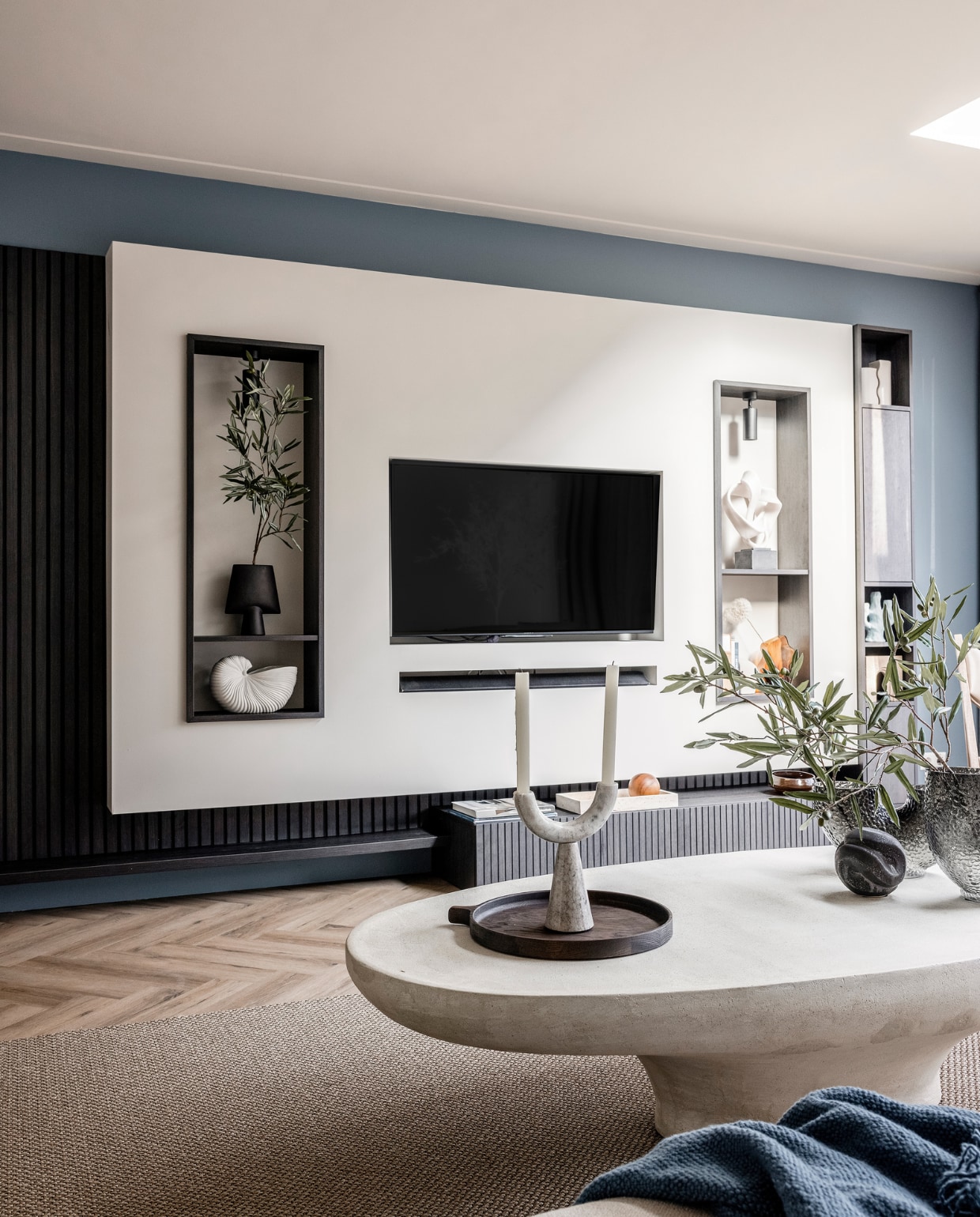 Verf muren bij de tv Denim Drift Flexa, Wandkast van de bewoners, geverfd in Sandy Beach Flexa, Wandmeubel met verticale lattenwand en ledverlichting Meijer Maat Interieurs, Bank Shark in de stof Sabbia 11 cream Eijerkamp, Vloerkleed Luca 6704 Cunera, Salontafel La Nena, Blauw plaid van Malagoon vtwonen, Marmeren siervorm met zware voet Nordal, Rond ornament Eijerkamp, Vazen Eijerkamp, Dienblad Eijerkamp, Kandelaar met twee armen Nordal, Kaarsen Hema, Olijftak 138217 Silk-ka. Overig privébezit Weer verliefd op je huis seizoen 17 aflevering 4 | styling Liza Wassenaar | fotografie Sonja Velda