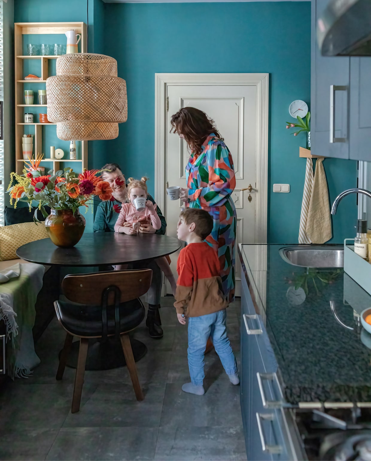 Muurverf Sapphire van Painting the Past. Tafel Wehkamp, stoelen Dutchbone, vaas Des Pots, bank gemaakt van kisten, matraskussen Nofruit, plaid Fatboy, geel kussen Sissy-Boy, groen kussen en hanglamp Ikea. Wandkast Jysk, mokken HKliving. Klok Studio Harm en Elke, handdoekhouder Woodendot, theedoeken Casa, vaas op wandplank Hay. Mokken met letters H&amp;M Home, plantenbak op aanrecht Ferm Living. Overig onbekend. vtwonen special binnenkijken 12-2023 | productie Cocofeatures | fotografie Anne den Haan