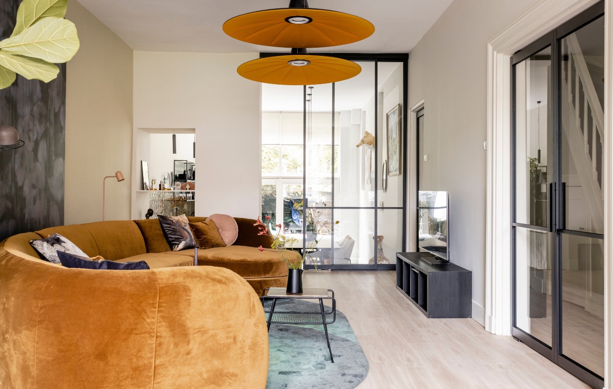 Verf muren Fine Cream Flexa, verf kast (naast de haard) Sandy Beach Flexa, wandpaneel met verlichting zelfgemaakt door Michiel Draaisma, behang op het paneel Canvas 313571 Eijffinger, pvc click vloer Blackjack Oak 2220 van Moduleo Woninginrichting-Aanhuis.nl, zwarte taatsdeuren, scheidingswand, schuifdeur GewoonGers, traptreden naar de keuken bekleed met blauwstalen neuzen en extreem off black leer uit de Stoer Chique collectie Upstairs, bank Connor Eijerkamp, vloerkleed Optical Eijerkamp, salontafel Glam Zuiver, hanglampen Lent Martinelli Luce, wandlamp op het wandpaneel Honore Lucide, vloerlamp achter de bank Buddy Eijerkamp, kussen (links op de bank) flowerbomb Muurmeesters, kussens onderdeel van bank Connor Eijerkamp, fluwelen kussenhoes (in het midden van de bank) Rembrandts kant, fluwelen kussen (rechts op de bank) kroonkraanvogel en melchior d’Hondecoeter Muurmeesters, rond roze kussen, zwarte vaas en houten kandelaar vtwonen. Overig privébezit. Weer verliefd op je huis seizoen 17 aflevering 5 | styling Frans Uyterlinde | fotografie Sonja Velda