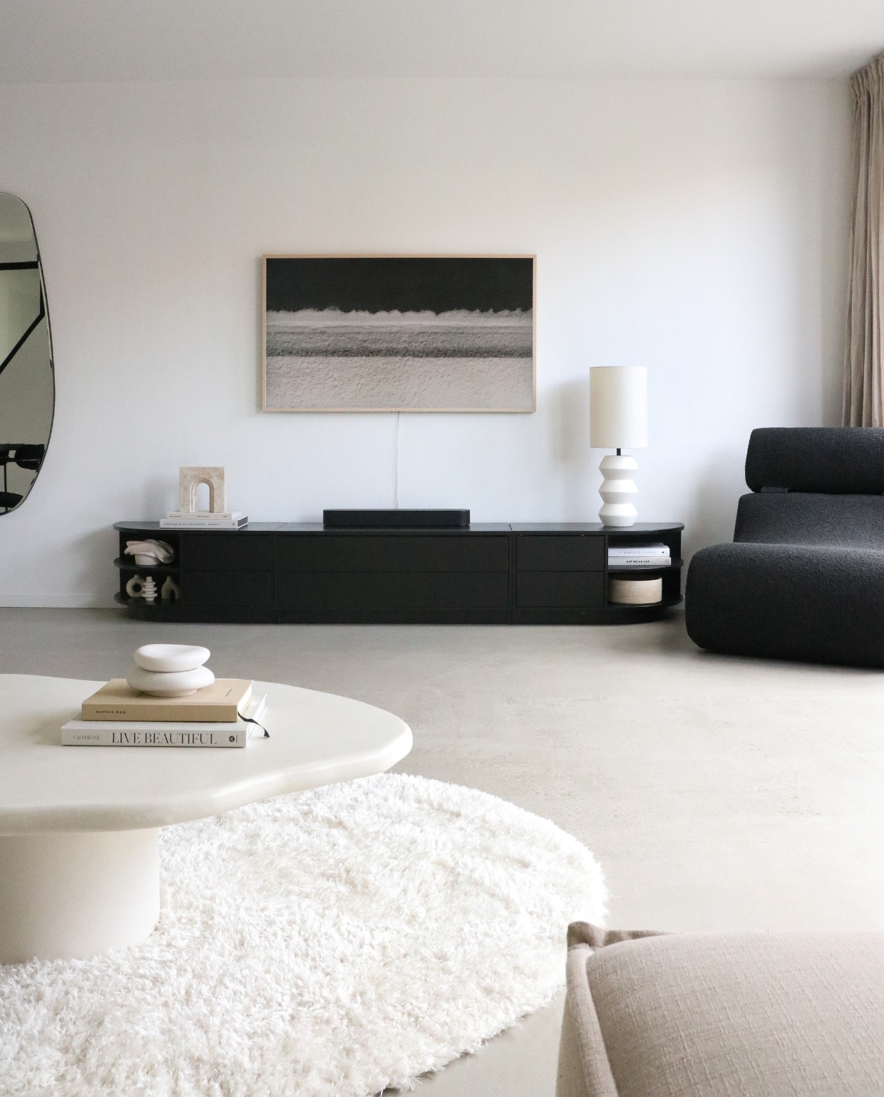 Betonciré salontafel She, vloerkleed Wehkamp, televisie Samsung, travertine object ‘Archus’ van Stoned Amsterdam, keramiek Creatrice Ceramics, tafellamp Kwantum, tv-meubel Finca van Woood, fauteuil Kave home, spiegel Blossholm. Overig onbekend. Styling en fotografie Manieke Versluis