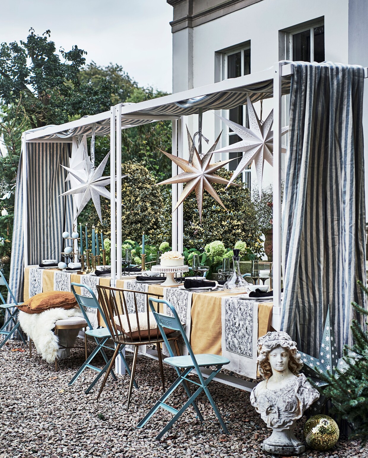 Tafels met bovenstel (com-anders.nl). Kerstbomen (janvanvulpenboomkwekerij.nl). Handgemaakte gerecyclede kerstballen, piek, klapstoelen (weldaad.com). Blauw blad met zilverkleurig accent in kerstboom, (silk-ka.nl). Kerstverlichting (tcdebosrand.nl). Papieren ei, maat XL, geel kussen, 50x50 cm, papieren kerstboom, 24 cm (h), papieren sterren (bungalow.dk). Discoballen (spektakelwonen.nl). Stompkaarsen, tafellakens, 140x240 cm, tafelloper, servet, set van 2, cocktailglazen, fles met zwarte stop, vierkante kandelaars, dinerkaarsen, set van twee, bankje (hm.com). Blauwe chocolade kerstballen (toutpatisserie.nl). Goudkleurige eetkamerstoel van Clayre &amp; Eef, 51x55x79 cm, schapenvacht Sheepskin van Weltevree, vierdelige serviesset Vera Wang Jardin van Wedgwood, bestek Mademoiselle van Villeroy &amp; Boch, 68-delig, messing dienblad van Oyoy Living Design(vtwonen.nl). Taart Pierrot (huizevanwely.nl). Goudkleurig plateau met drie lagen (nhflowers.nl). Lantaarns (allestedlund.com). Kandelaars (wildschut-antiques.com). Buste (harlequin-lisse.biz). Goudkleurig kussen (nordal.eu). Gestreepte doek Endless Summer Stripe van Barbara Osório, 310 cm (l) (wva.nl). vtwonen 12-2021 | styling Liza Wassenaar | fotografie Sjoerd Eickmans