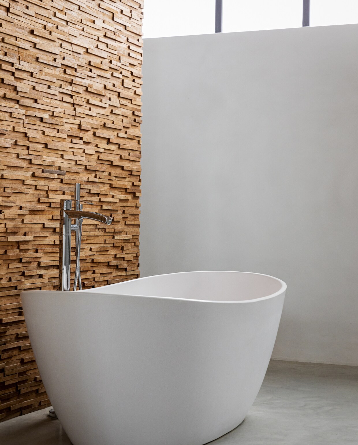 Vrijstaand ligbad matwit composiet Solid Surface. Houten wand Teak Wood Cladding van Michel Oprey &amp; Beisterveld. vtwonen 01-2022 | styling Ilona Jongepier | fotografie Dana van Leeuwen
