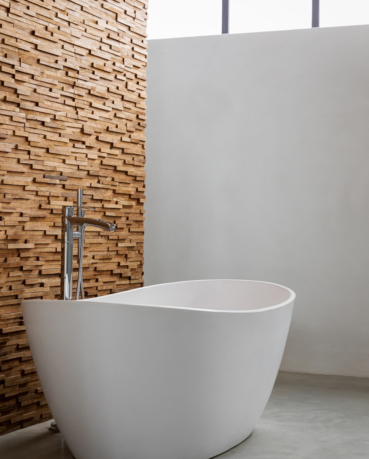 Vrijstaand ligbad matwit composiet Solid Surface. Houten wand Teak Wood Cladding van Michel Oprey &amp; Beisterveld. vtwonen 01-2022 | styling Ilona Jongepier | fotografie Dana van Leeuwen