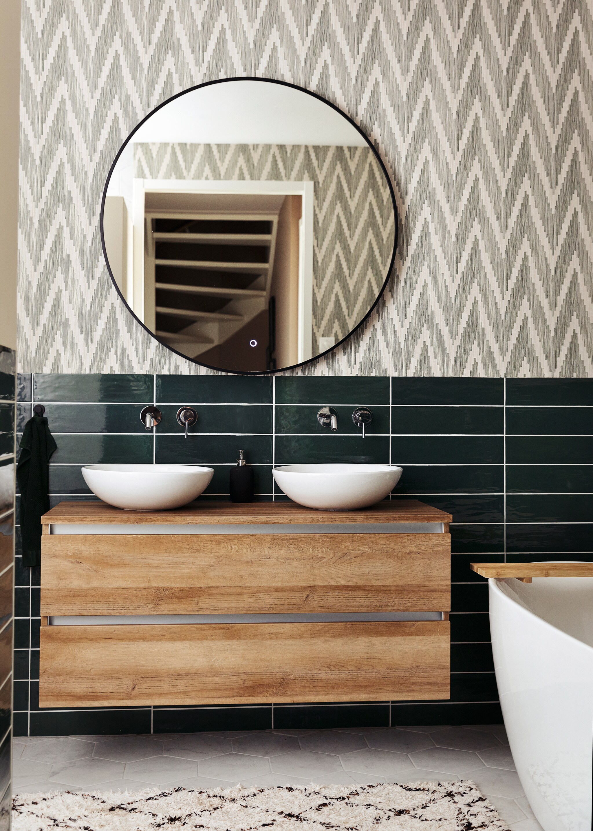 Badkamerkast Unihopper. Wastafelkommen Solid Surface. Kranen en vrijstaand bad ADW. Spiegel Best Design. Tegels Sartoria. Behang BN Walls. Kleed H&amp;M Home. vtwonen 10- 2021 | styling Ilona Jongepier | fotografie Dana van Leeuwen