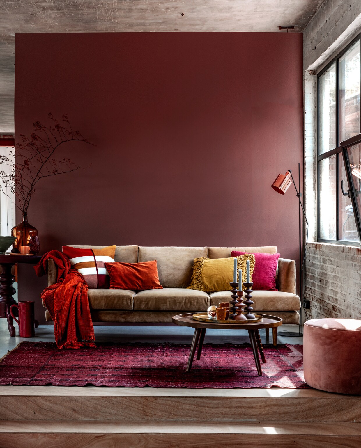 Muurverf Pure zijdemat Full Plum (Flexa). Beige velours 3-zitsbank Floyd, 214x88x81 cm (bxdxh), velours vintage Rosa poef (Sofacompany). Roestbruine crinkle plaid van Hay, vloerlamp Masterlight Industria 1020, hoogte 161 cm, okergeel kussen met franjes van Madam Stoltz (vtwonen.nl). Kussen met gekleurde vlakken, roestbruin velours kussen, okergeel kopje, okergeel bord (H&amp;M Home). Donkerfuchsia kussen Milazzo Peony van Designers Guild (Wilhelmine van Aerssen). Wijnrode bijzettafel (Combitex). Donkergele flesvaas (Van Dijk &amp; Ko). Olijfgroene schaal, donkerrode kan (In-Petto). Vloerkleed (Ochre and Red). Salontafel Arabica van Dutchbone, kandelaars, presse-papier met bloem (Woondock). Roestbruine kopjes (Intratuin). vtwonen 11-2018 | Styling Moniek Visser | Fotografie Peggy Janssen