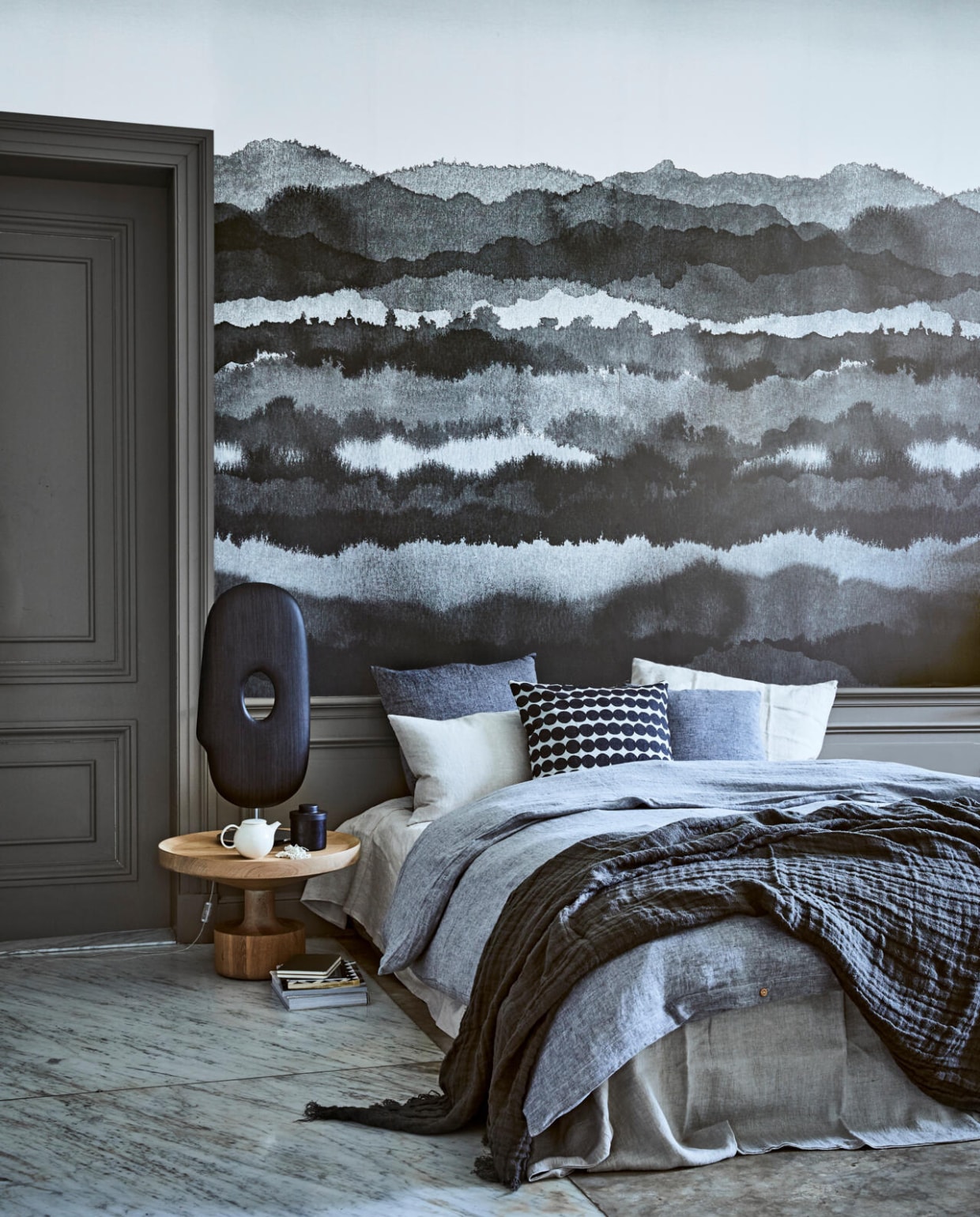 Behang Midnatt darkgrey van Sandberg, 180x270 cm (bxh) (De Ru). Eikenhouten bijzettafel Kigi(Linteloo). Lamp Mask van Moooi(Homestede). Theepotje Pebble, potje met deksel (Six and Sons). Laken Flax linnen 160x260 cm, dekbedovertrek Pebble linnen 200x200 cm, kussen Charcoal 60x60 cm, kussen Charcoal 50x50 cm, kussen Flax 40x60 cm, kussensloop Seashell linnen vanaf 60x70 cm (By Mölle). Kussen met stipdessin van Marimekko (&amp;Klevering). Ketting (Pols Potten). Plaid van grijs linnen, 130x170 cm (Hoffz). Boek en tijdschriften privébezit. vtwonen 02-2018 | styling Cleo Scheulderman | fotografie Jeroen van der Spek