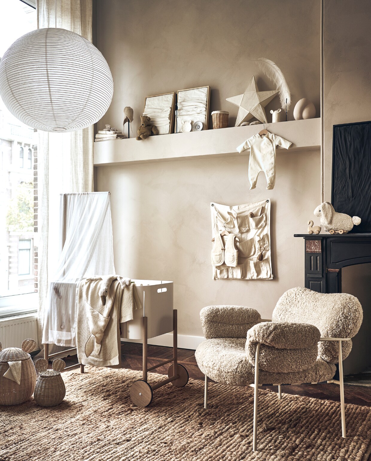Grote lamp van Hay (loods5.nl). Babybed, beige deken, pittenzak gans, handdoek konijn, lakens, beige sloffen, beige muts, knuffelbeer, bord met letter D van Anouk Kramer, extra small, witte sterlamp, babysloffen met schapenvacht, wit babypakje, houten zwaan, wit konijn met touwtje, witte vakkenzak, witte bodywarmer, konijnenbijtring (thearchivestore.com). Rieten mand op plank, rieten manden met oor, groot en klein, wit bord met oren, wit bakje met oren, rieten rammelaar, kam (zarahome.com). Witte kunst drieluik Triptych Water &amp; Air, 30x40 cm, zwart kunstwerk Water &amp; Cracked Mud, 60x80 cm (studio-harte.com). Veer op staander (taxidermy.nl). Sierbol op plank (eijerkamp.nl). Beige stoel met witte poten (homestede.nl). Muurverf onbekend. Overig privébezit. vtwonen 01-2023 | styling Liza Wassenaar | fotografie Sjoerd Eickmans