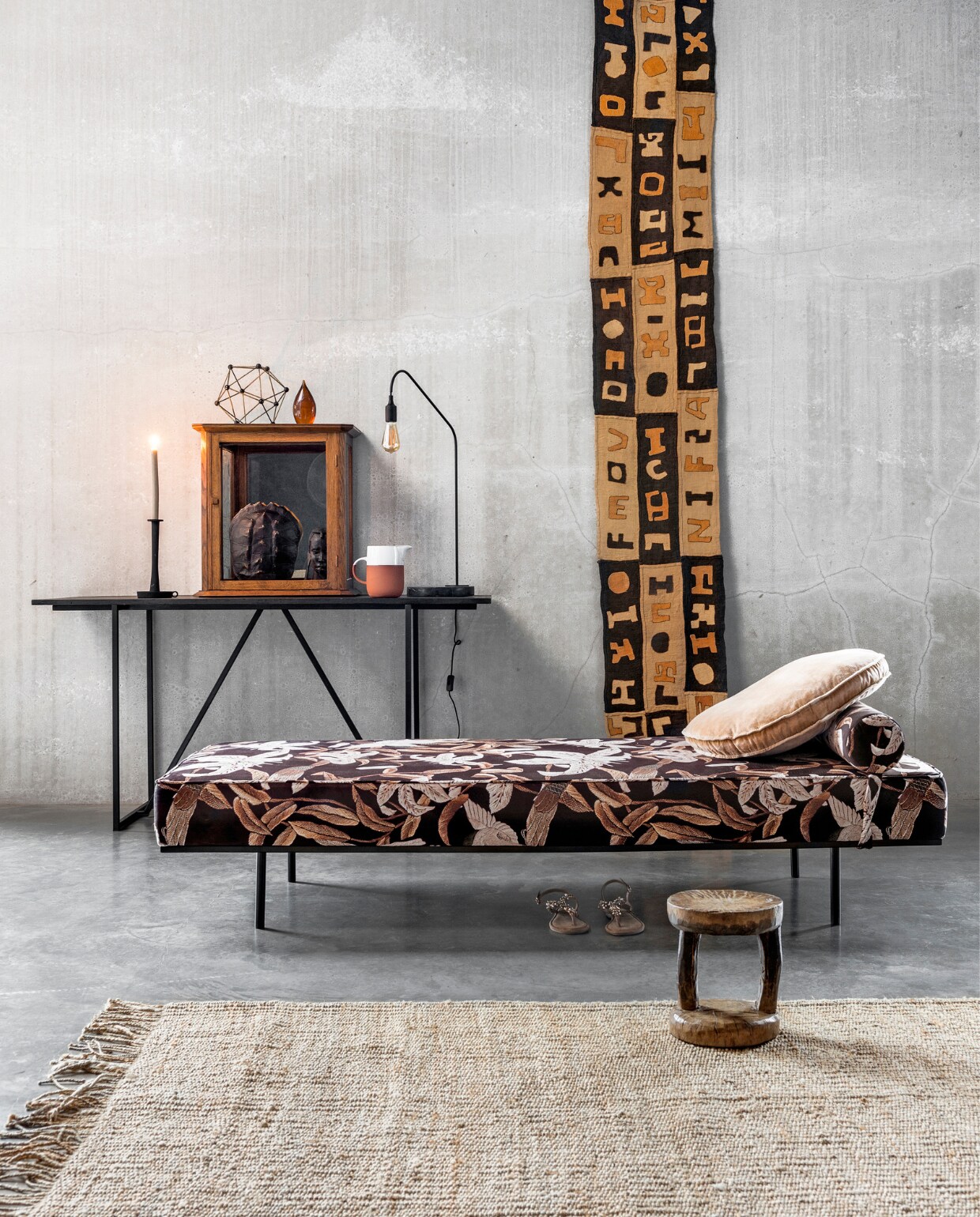 Daybed, 200x80x41 cm (lxbxh), rond kussen, vloerkleed van jute, 200x300 cm, steenoranje glazen presse-papier, object moleculair, kunst schildpadschild (HK Living). Wandtafel, 160x60x80 cm (lxbxh), lamp met marmeren onderstel (Nettie de Groot). Kandelaar (vtwonen.nl). Kan van terracotta met wit glazuur (By Mölle). Vitrinekastje (De Weldaad). Wandkleed van oude Kuba borduursels (ML Fabrics). Houten Batonga kruk (Couleur Locale). Sandalen (Tamaris). vtwonen 02-2018 | Styling Marianne Luning | Fotografie Stan Koolen