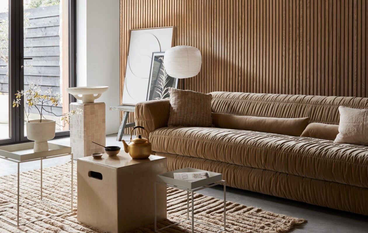 Akoestische wandpanelen van eikenhout en beige vilt, 60x240 cm (bxh) (noakk.nl). Bank Club Couch in Royal Velvet Cream, 108x74x72 cm (bxdxh) (hkliving.nl). Wollen vloerkleed Crease van Ferm Living, 250x160 cm (bxh), katoenen kussen links Febbie van Bloomingville, 45x45 cm, papieren schaal Earth van Serax (vtwonen.nl/shop). Linnen kussen rechts, 50x30 cm (sukha.nl). Rijstpapieren lampenkap Common, 44x39 cm (Øxh), lichtgrijze stalen salontafel Tray, 30x30x34 cm (lxbxh), witte stalen salontafel Tray, 60x40x39 cm (lxbxh) (hay.nl). Tadelakt tafel Cube, 40x40x40 cm (bxdxh), tafel met zelliges, 30x30x60 cm (bxdxh), tadelakt vaas, theepot, kom, walnoothouten schaal (householdhardware.nl). Poster Solidago Gigantea ll van Printedplant, 50x70 cm (pstrstudio.com). Reliëf kunstwerk, 83x103 cm (bxh) (hkliving.nl). Overig privébezit. vtwonen 08-2023 | styling Fietje Bruijn | fotografie Alexander van Berge
