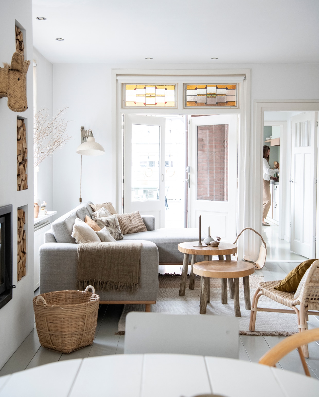 Doorkijkje naar de keuken. Rotan stoel Ikea. Mand vtwonen. Salontafels, plaid, kussen Aai Made with Love Loods 5. Bruine kaars Søstrene Grene. Grijze kaars Kwantum. Vaasje kringloopwinkel. Kleed Zara Home. Wandlamp zelf samengesteld. Bank Sofa Company. Kussens Zara Home, Søstrene Grene, Made by Mom. vtwonen special DIY 3-2021 | productie Inside Homepage | styling Janneke Peters | fotografie Louis Lemaire