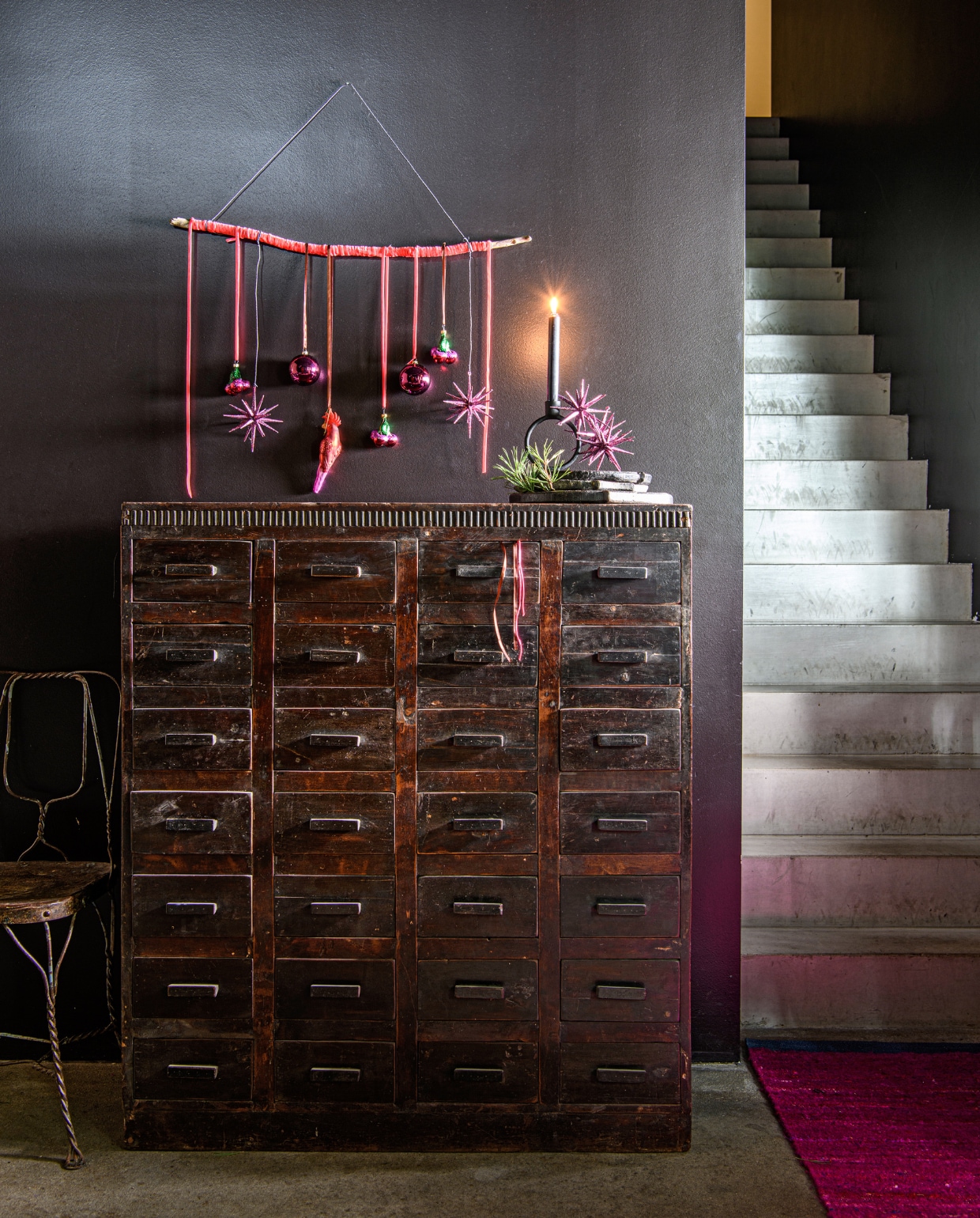 Zwarte teakhouten vintage kast met 28 lades, 107x37x121 cm (bxdxh) € 3045,-, zwart stenen bord € 35,95, maat L € 41,95, vintage stoel India € 159,- (rawmaterials.eu). Zwarte stenen kandelaar Bobbili € 14,95 (thingsilikethingsilove.com). Vloerkleed silk roze van HKliving, 120x180 cm (bxl) vanaf € 319,- (debijenkorf.nl) vtwonen bijlage kerst 2023 | styling Marit Saladini | fotografie Louis lemaire