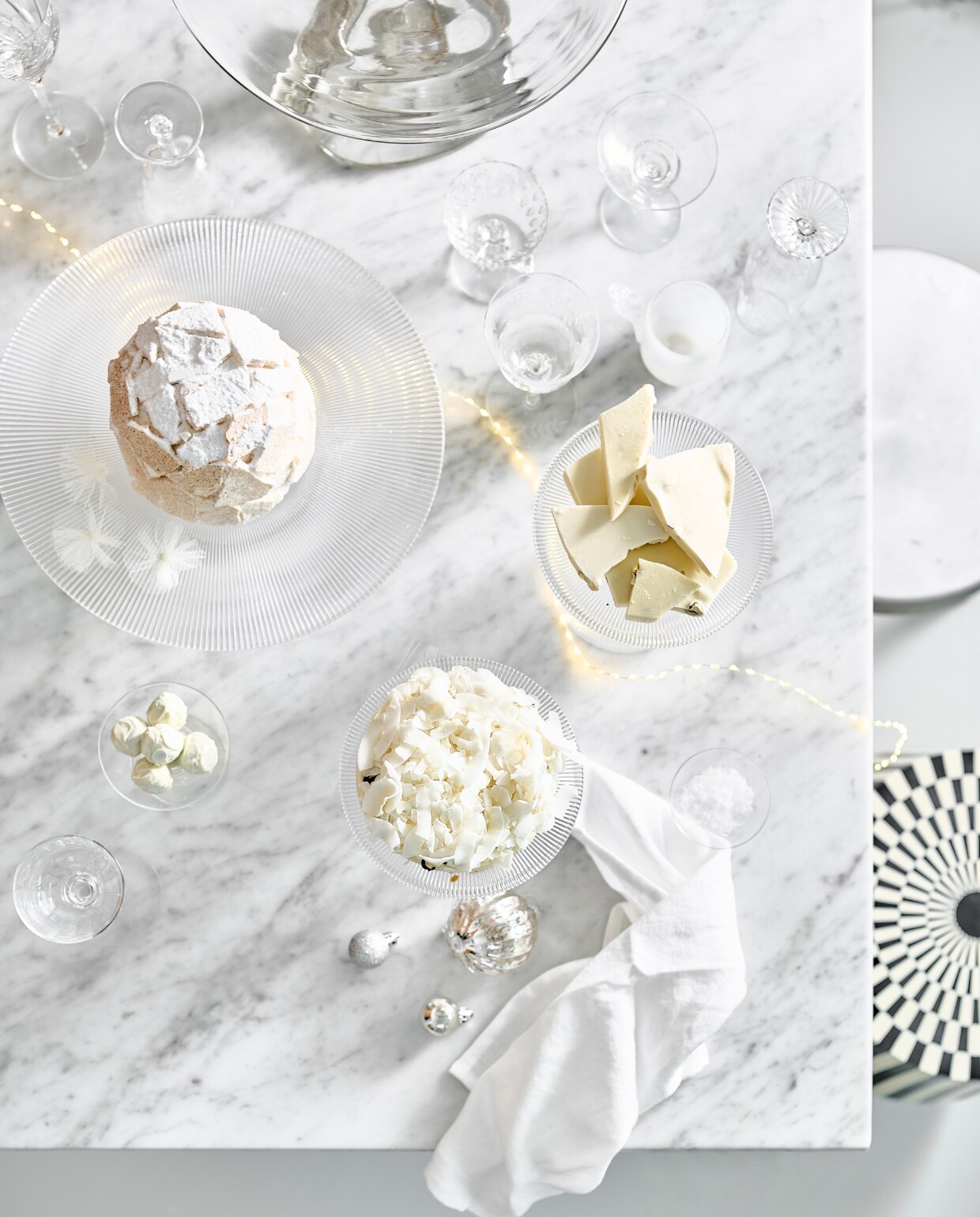 Taartplateaus van geribbeld glas Fig, in drie maten vanaf € 41,67, zwart-witte kruk, mdf met mangohout € 530,30 (nordal.com). Aluminium kruk Tasca € 595,- (framacph.com). Linnen servet, set van 2 € 15,99 (zarahome.com). Massief glazen etagère Damo van Ferm Living € 239,- (vtwonen.nl). Tweedehands glazen vanaf € 0,20 (kringloopwinkel). IJstaart prijs op aanvraag (huizevanwely.nl). Lichtsnoer € 32,50 (two-gether.nl). Kleine onbreekbare kerstballen van House of Seasons, set van 24 € 14,95 (bol.com). Geribbelde kerstbal, set van 2 € 7,99 (hm.com). vtwonen bijlage kerst 2023 | styling Kim van Rossenberg | fotografie Sjoerd Eickmans