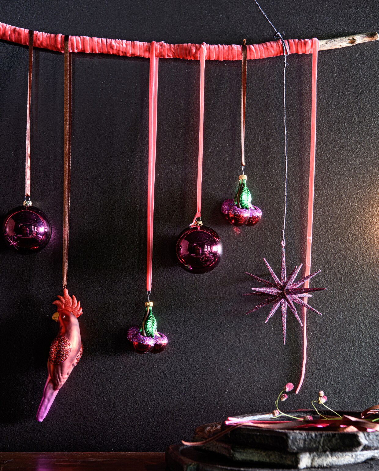 v.l.n.r. velours lint roze 5 mm per rol vanaf € 1,99 (intratuin.nl). Framboos kunststof roze ronde kerstballen, glans/mat, per 20 stuks € 13,- (blokker.nl). Glazen ornament papegaai vanaf € 2,99, roze/groen ornament kers vanaf € 2,99, glitter ster ornament vanaf € 2,99 (intratuin.nl). vtwonen bijlage kerst 2023 | styling Marit Saladini | fotografie Louis lemaire