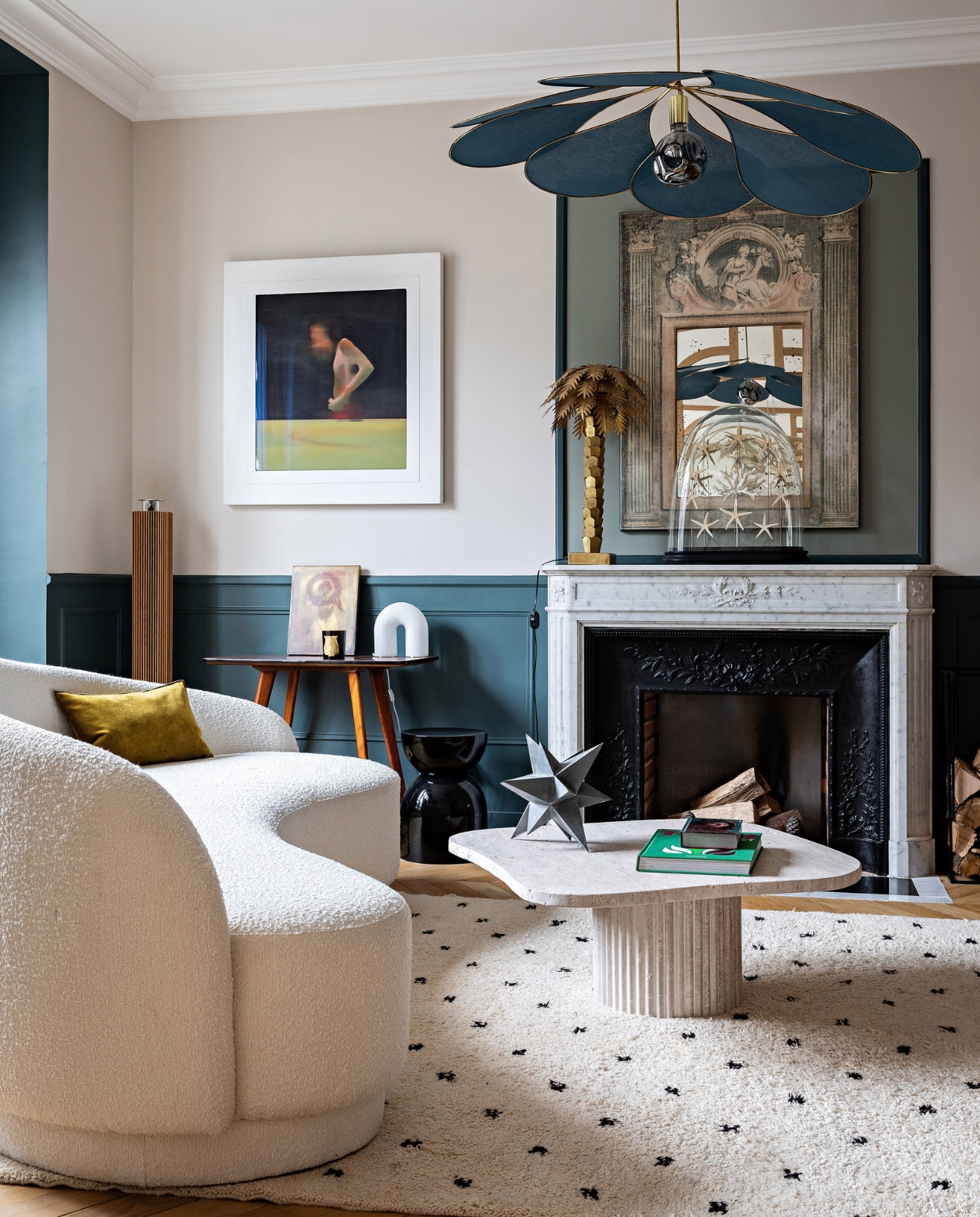 Vloerkleed Mustapha Blaoui. Sofa zelf ontworpen en bekleed met bouclé van Élitis. Hanglamp Edmond van Opjet, salontafel Roche Bobois, kussen Élitis. Sidetable en glazen stolp vlooienmarkt, schilderij Étienne Assénat, spiegel erfstuk, palmboom HKliving. Verfkleuren lambrisering Skimming Stone en Stiffkey Blue en muurverf Elephant’s Breath van Farrow &amp; Ball. Overig onbekend. vtwonen 12-2023 | productie AC Scoffoni | styling Marie-Maud Levron | fotografie Yann Deret | tekstbewerking Merel van der Lande