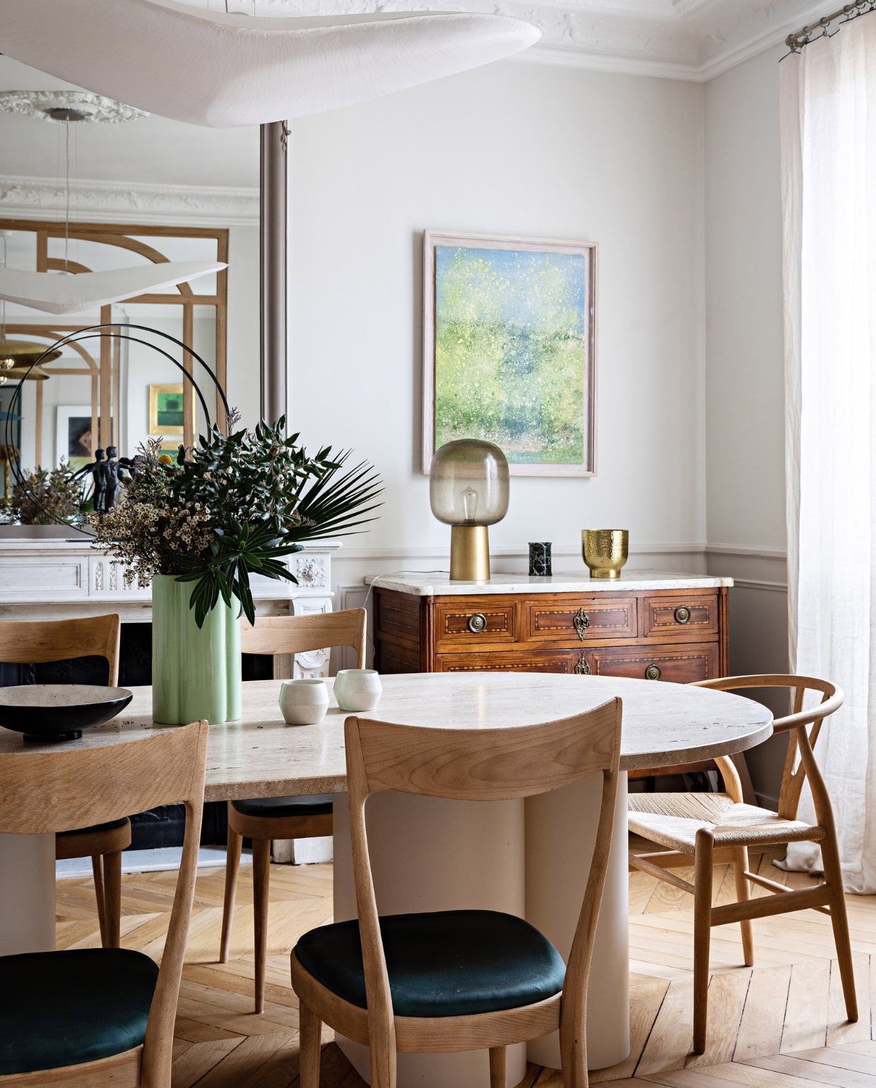 Stenen tafel Bateaumagne, stoelen rommelmarkt in Normandië, hanglamp Céline Wright, schilderij Antoine Vit. Ladekast en spiegel erfstuk. Gouden vaas H&amp;M Home, groene vaas India Mahdavi, zwart-witte schaal vlooienmarkt, waxinelichthouders Monoprix, gordijnen Caravane. Vloer lag al in het huis. Overig onbekend. vtwonen 12-2023 | productie AC Scoffoni | styling Marie-Maud Levron | fotografie Yann Deret | tekstbewerking Merel van der Lande