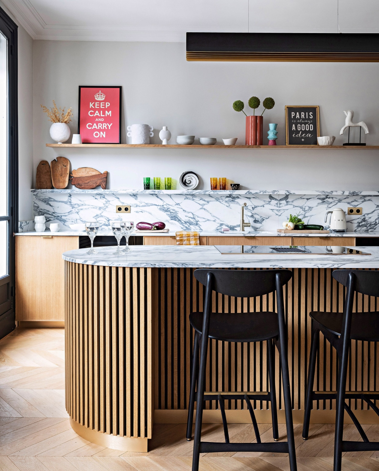 Keuken zelf ontworpen met marmer Arabescato Corchia van Spadaccini, op maat gemaakt door Ceramica. Barstoelen Timber Black van 366 Concept, hanglamp Respiro van Dcw Éditions, houten snijplanken Monoprix. Gekleurde glazen, wit servies en beeld vlooienmarkt. Wijnglazen Christofle, koperkleurige vaas India Mahdavi, lichtschakelaars Modelec. Overig onbekend. vtwonen 12-2023 | productie AC Scoffoni | styling Marie-Maud Levron | fotografie Yann Deret