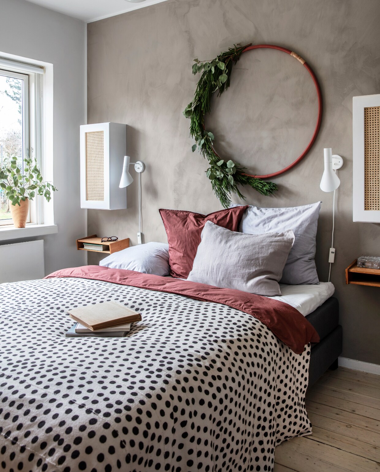 Ook de slaapkamer kreeg kerstdecoratie. Muur geverfd met Lady Minerals kalkverf van Jotun in de kleur Warm Grey, sprei van AfroArt, textiel van Broste Copenhagen. De kleine wandkasten zijn gemaakt van boekenkasten met kastdeuren die Rikke heeft bekleed met webbing. vtwonen 13-2019 | styling Rikke Graff Juel | fotografie Christina Kayser O.