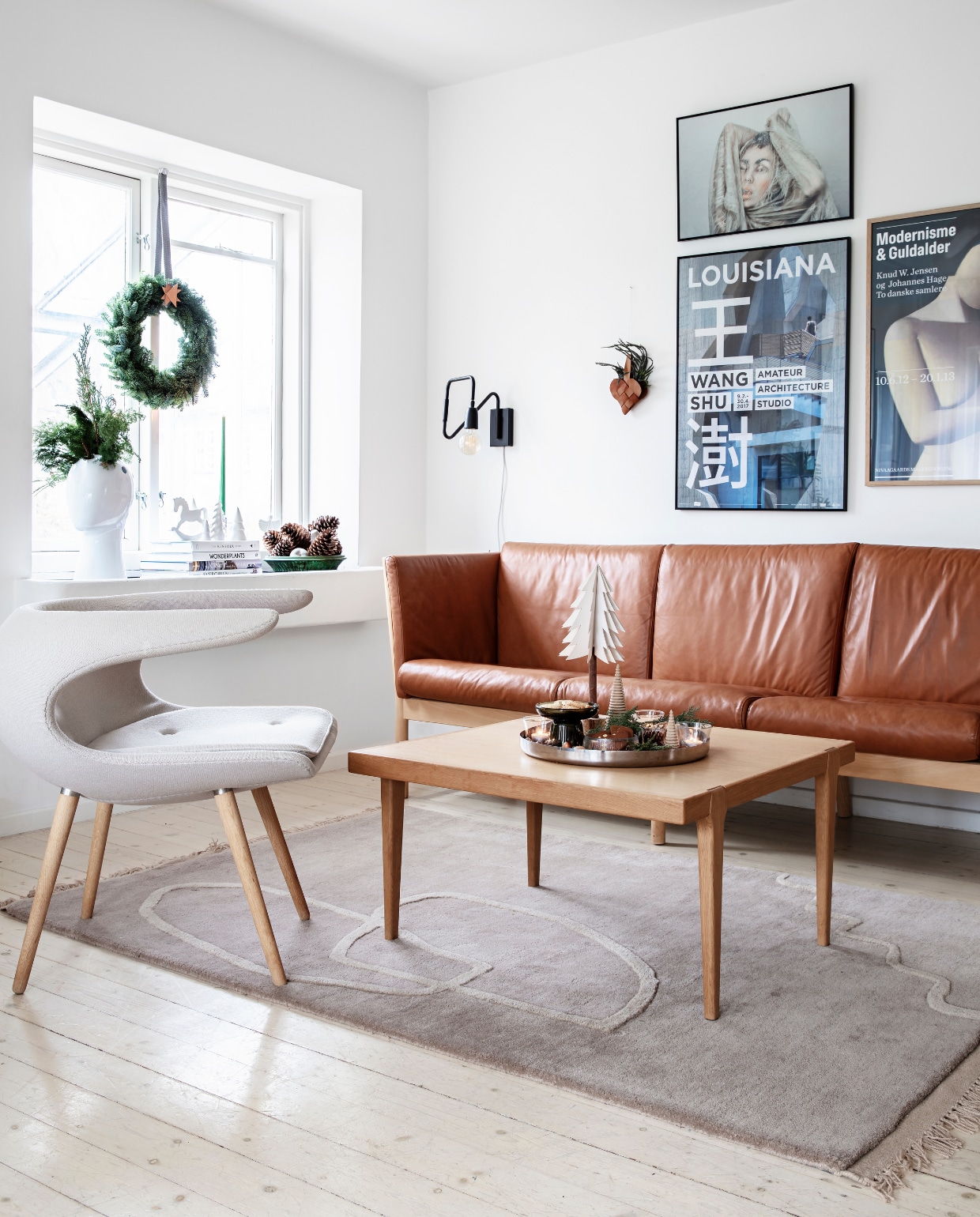 Hout, leer en keramiek spelen een belangrijke rol in huis. Bank van Skovby Furniture, vintage salontafel van Børge Mogensen, fauteuil van Stouby. Kleed van Ferm Living. Op tafel zelfgemaakte kerstkoekjes in kleine glazen, omringd door noten, pijnboomtakjes en kleine en grote kerst- bomen van hout die Rikke zelf maakte. vtwonen 13-2019 | styling Rikke Graff Juel | fotografie Christina Kayser O.