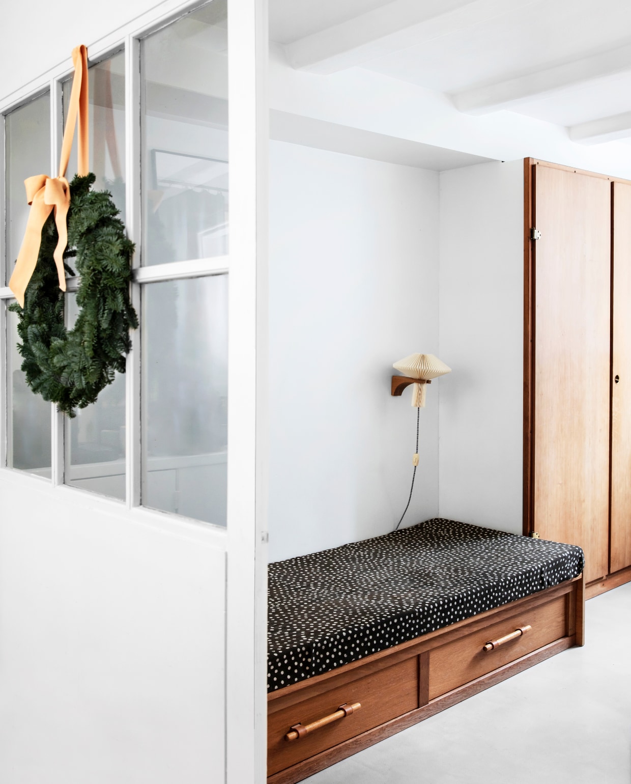 De logeerkamer op de benedenverdieping. Het daybed uit de jaren 50 kan worden omgebouwd tot tweepersoonsbed. De wandlamp van Le Klint is vintage. De ingebouwde kasten in het hele huis zijn van Børge Mogensen en Grethe Meyer. Ze zaten al in het huis toen Rikke en Jeppe het kochten. Ontbrekende exemplaren wisten ze alsnog te vinden. vtwonen 13-2019 | styling Rikke Graff Juel | fotografie Christina Kayser O.