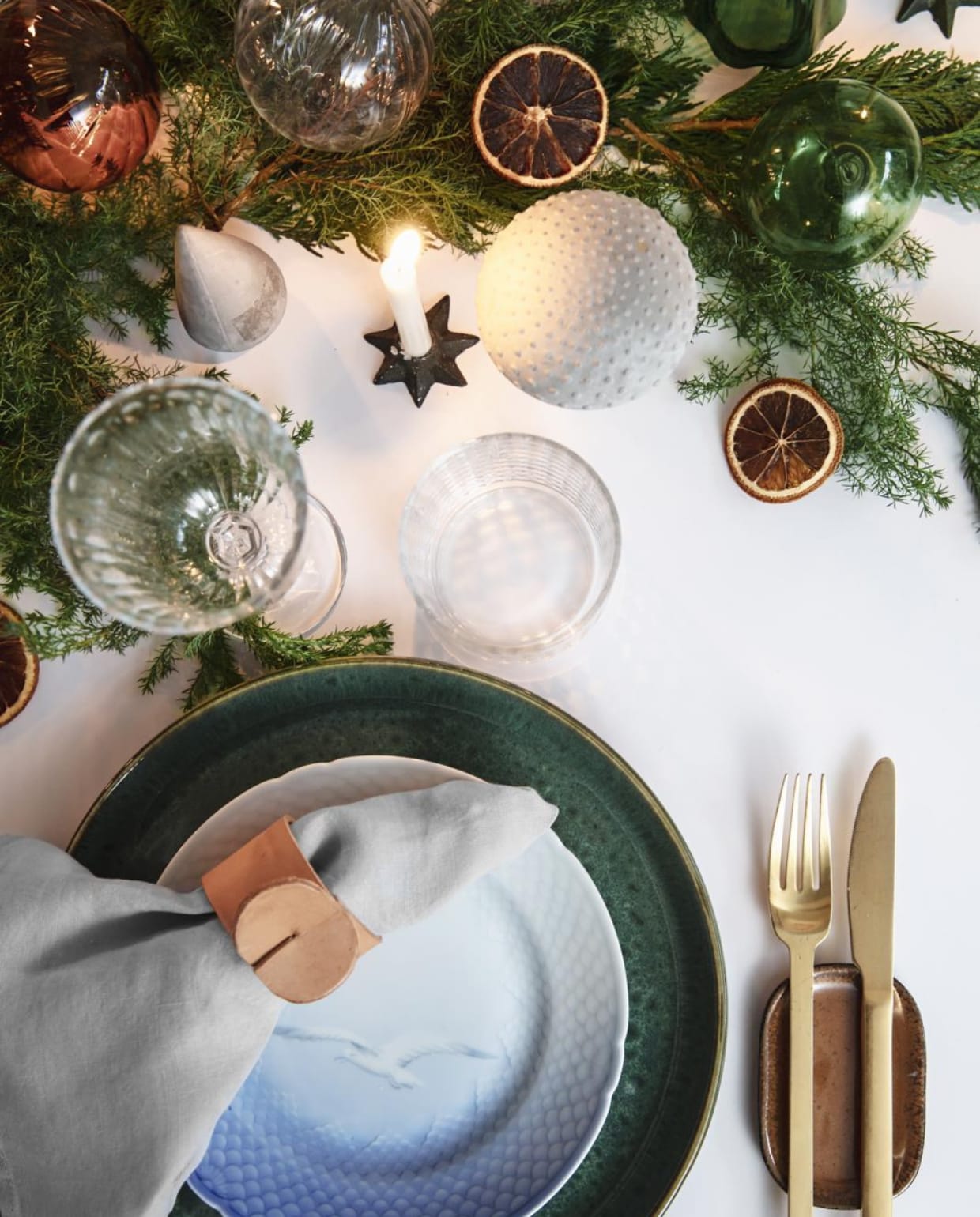 Het groen van de takken, samen met het leer en hout, bepalen de sfeer op de kersttafel. De leren servetringen maakte Rikke zelf. vtwonen 13-2019 | styling Rikke Graff Juel | fotografie Christina Kayser O.