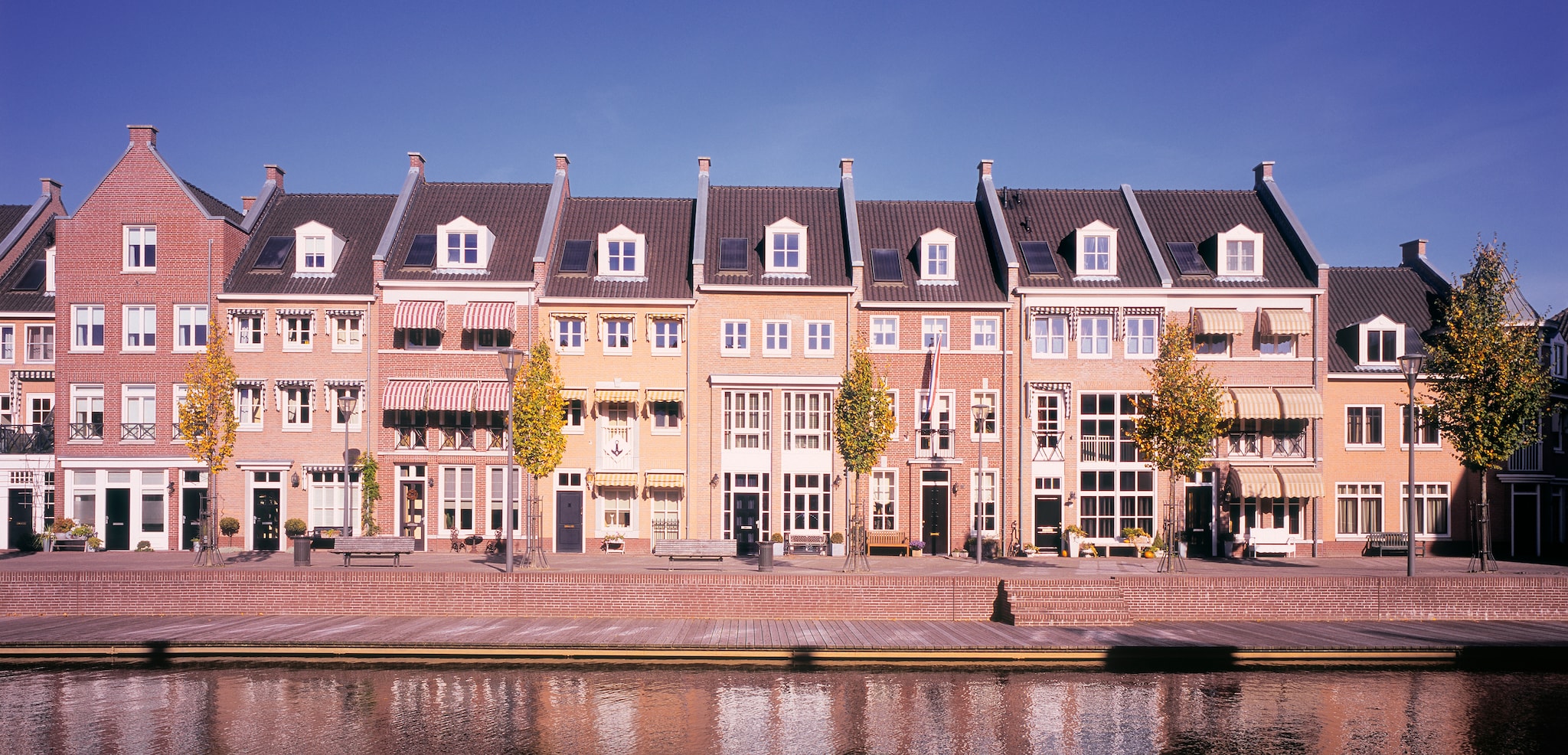 Newly built homes in traditional style alongside canal. Panorama image shot in The Netherlands. Getty Images