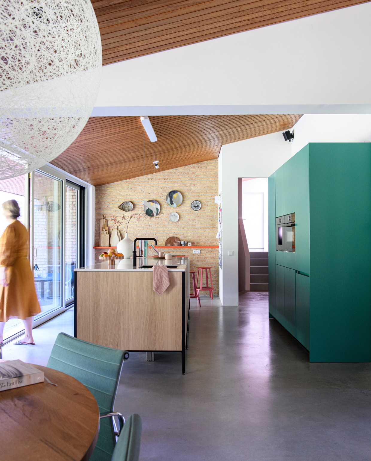 Muurverf Ral 9010 van Sikkens. Keuken Cesar van Via Creaties, fruitschaal Oyoy Living Design, servies op aanrecht Normann Copenhagen, theedoek Hema, kraan Quooker, smalle houten planken HKliving, overige planken onbekend, borden met vrouwenprint Ferm Living, barkrukken Hay. Regenboog-dienblad en kom Oyoy Living Design. Overig onbekend. vtwonen special binnenkijken 12-2023 | productie Inside Homepage | styling Inge van Lieshout | fotografie Louis Lemaire