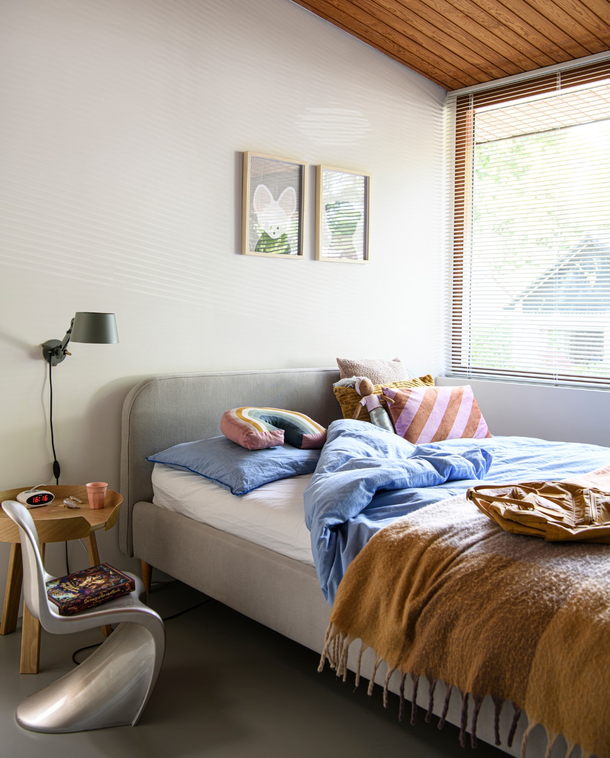 Muurverf Ral 9010 van Sikkens. Bed KidsDepot, dekbedovertrek en regenboog-kussen H&amp;M Home, kussens Kwantum, gele deken Jysk, gele tas Fjällräven Kånken. Nachtkast Muuto, wandlamp Tonone Bolt, roze mok HKliving. Overig onbekend. uurverf Ral 9010 van Sikkens. Kledingrek HKliving, kunstwerk Sjer Jacobs, spiegel Ikea. Overig onbekend.