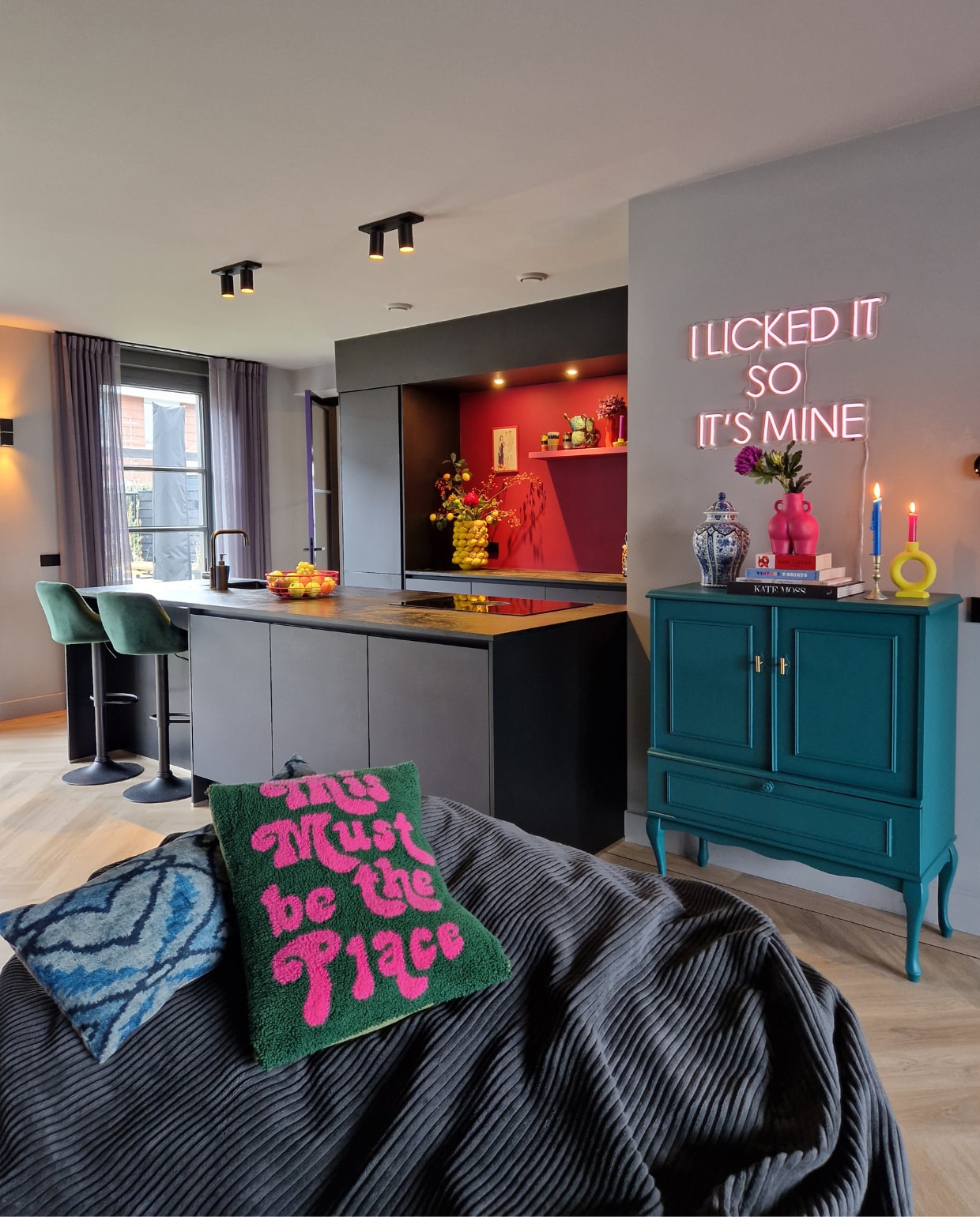 Barkrukken Amazon. Fruitschaal Kwantum, roze geverfd. Vazen in nis Stoer Wonen. Schilderij van Sooflexie. Mokken en kandelaar HKliving, geel geverfd. Mokken Kwantum. Muurverf boven aanrecht Bloos van Praxis. Kussen en neonlicht Etsy. Kussen met tekst Macrame Punch Studio. Antieke kast geverfd in IG PS-1172 van Karwei. Vaas met deksel erfstuk. Vaas Kwantum, roze geverfd. Kandelaar de Bijenkorf, geel  geverfd. Muurverf IG KH M-116 van Karwei. Zitzak Vetsak. Overig onbekend. vtwonen 2023-13 | Fotografie Anne Marie Vandersteen