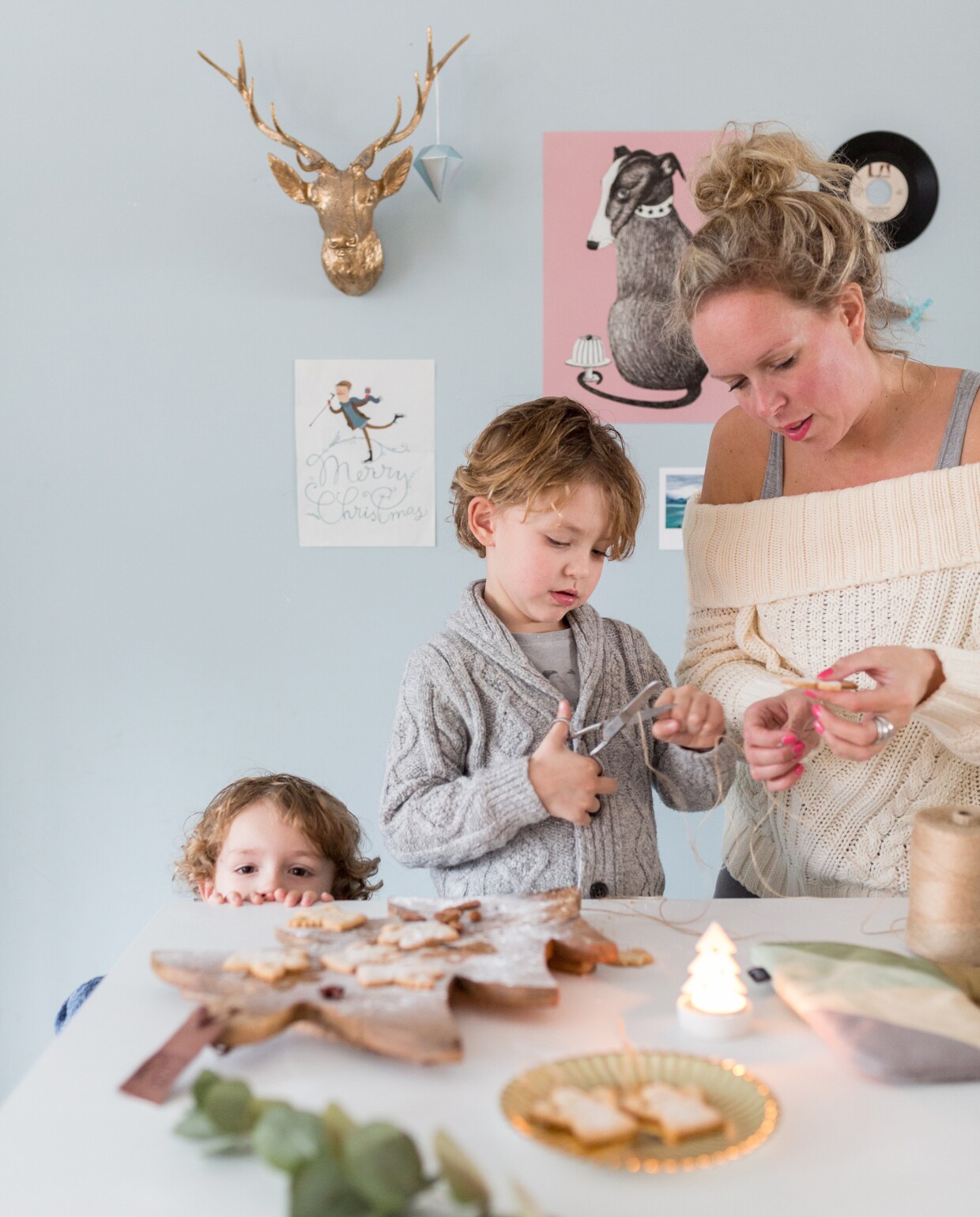 Faas, Vic en Sabine bakken kerstkoekjes in de keuken. Op de achtergrond een verzameling posters, gescheurd uit een blad en van de Walnut Mixstore (roze met hondje), een door Sabine zelf goud gespoten hertenkopje van de Action en een singeltje. vtwonen kerstspecial 2016 | fotografie Hans Mossel | styling Sabine Burkunk | tekst Seline Steba
