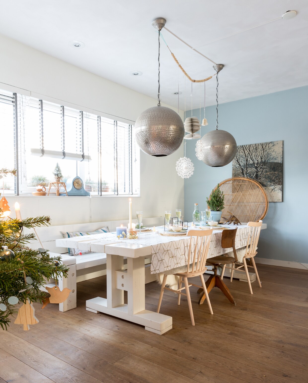 De lampen van Laif &amp; Nuver tikte Sabine ruim voordat het huis klaar was al op de kop. ‘Ik wist dat ze mooi zouden uitkomen bij de hoge plafonds, ze hebben nog een hele tijd op de zolder van de winkel op me liggen wachten. Door de kleine gaatjes krijg je zo’n 1001-nacht sfeertje, heel gezellig.’ De enorme tafel en bijpassende bank werden door een bevriende timmerman op maat gemaakt van dikke balken. Het tafelkleed is van Present Time, de stoelen van Dille &amp; Kamille (spijlen) en Loods G (oude bureaustoel). De pauwenstoel vond Sabine voor een prikkie bij de kringloop, het schouwklokje in de vensterbank komt daar ook vandaan. Ze verfde hem blauw met muurverf. De woonketting is van Xenos, alle kerstversiering van Dille &amp; Kamille. vtwonen kerstspecial 2016 | fotografie Hans Mossel | styling Sabine Burkunk | tekst Seline Steba