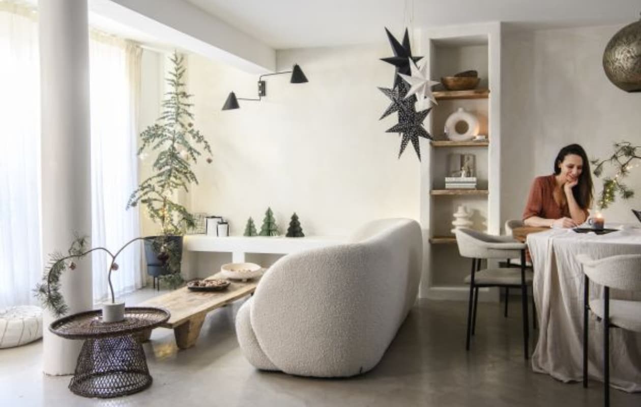 Vloer Tav Microcement, muurverf Fresco in Bone van Pure &amp; Original. Gordijnen Amphora 02 en eetkamerstoelen River van Dotshop. Driezitsbank Paul van Sofacompany. Salontafel Nagaland en schalen in kast Vanheesdesign. Gevlochten bijzettafel, zwarte schaal en zwart kaarsplateau Raw Materials. Zandkleurige schaal en zwart-witte kerststerren Loods 5. Poef Household Hardware, blauwe ceder Intratuin. Ornamenten, vazen en tafelkleed H&amp;M Home. Plantenpot Tuincentrum Osdorp, cadeaudozen verzameld. Uitvouwkerstbomen Hema en MrsBloom. Wandlamp en zwarte kerstster House Doctor. Doos met ingelegde droogbloem Loesje van Herp, tafel HKliving, hanglamp Ball Filigrain XXL van Zenza Home, kaars Casa. vtwonen 13-2023 | productie Insidehomepage | fotografie Louis Lemaire  tekst Mirjam Rosema-Verhulst