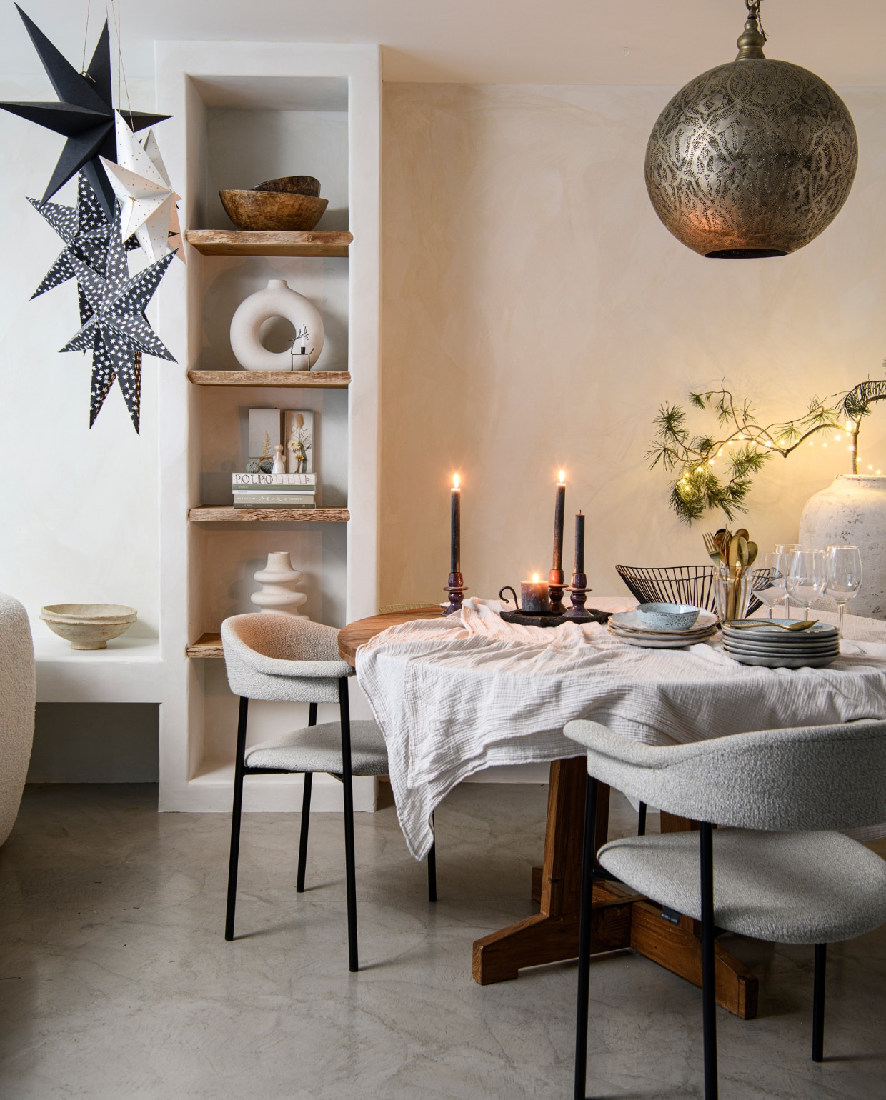 Vloer Tav Microcement, muurverf Fresco Bone van Pure &amp; Original, witte schaal op bank Nordal, zwarte kerstster House Doctor, zwart-witte kerststerren Loods 5. Schalen in kast en kruidenpot op tafel Vanheesdesign. Vazen en tafelkleed H&amp;M Home. Doos met ingelegde droogbloem Loesje van Herp, eetkamerstoelen River van Dotshop, tafel HKliving, hanglamp Ball Filigrain XXL van Zenza Home, kaarsen Casa, kaarsplateau Raw Materials, servies House Doctor, bestek Bolia, draadschaal Serax, wijnglazen Hema. vtwonen 13-2023 | productie Insidehomepage | fotografie Louis Lemaire  tekst Mirjam Rosema-Verhulst